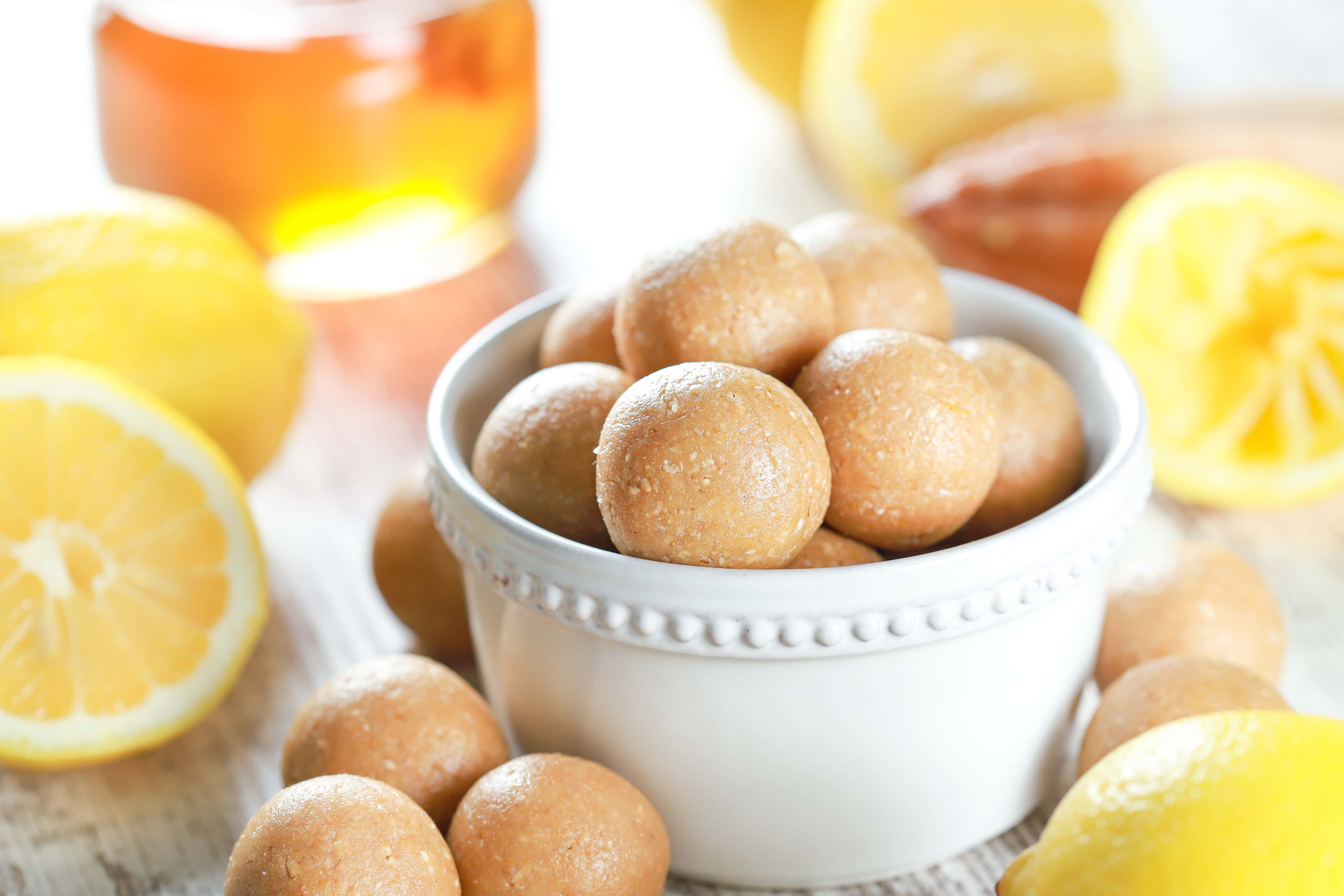 Lemon energy balls in a small white bowl with more in the foreground. Recipe from A Kitchen Addiction