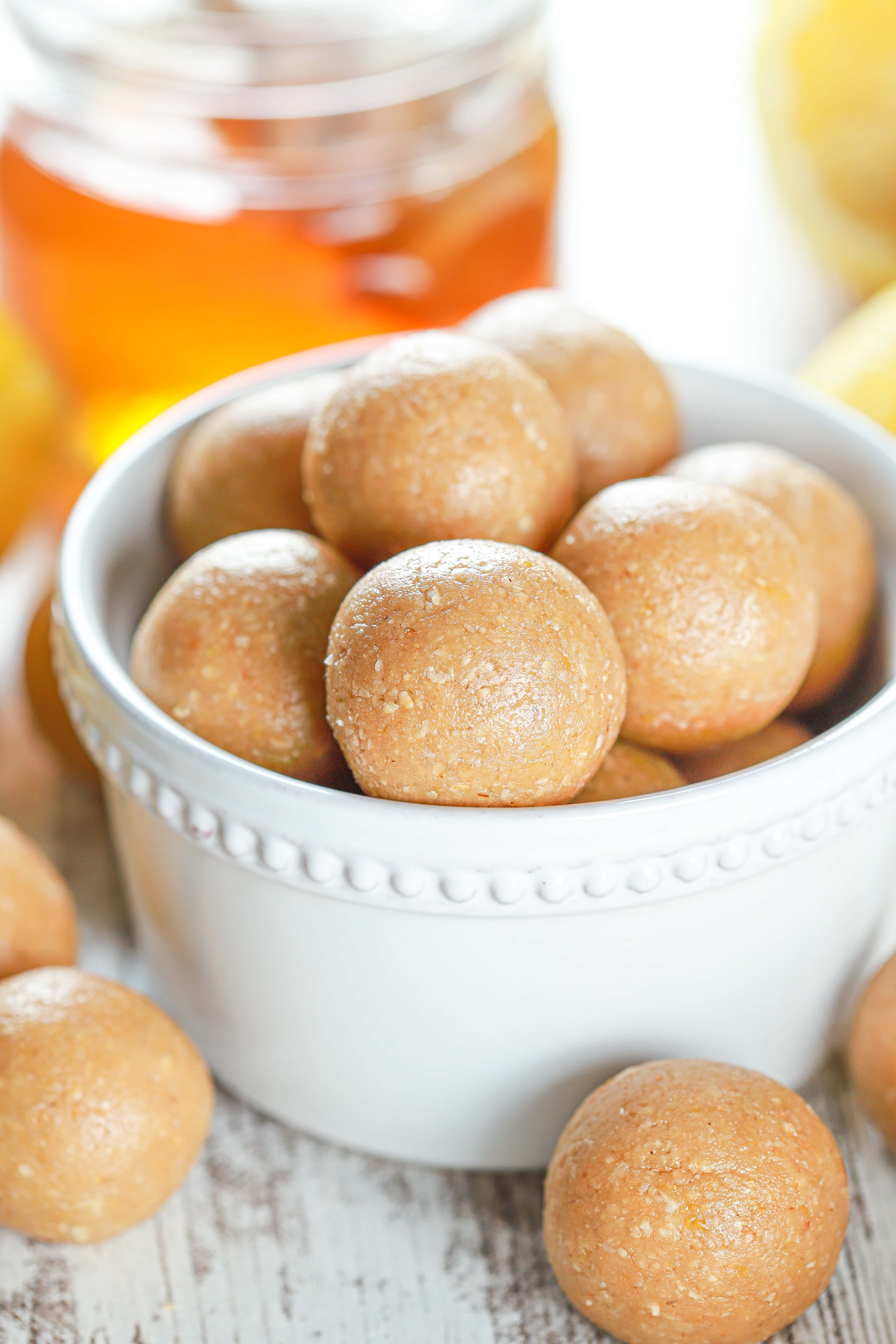 Lemon Protein Bites in a small white bowl with a jar of honey in the background. Recipe for bites from A Kitchen Addiction