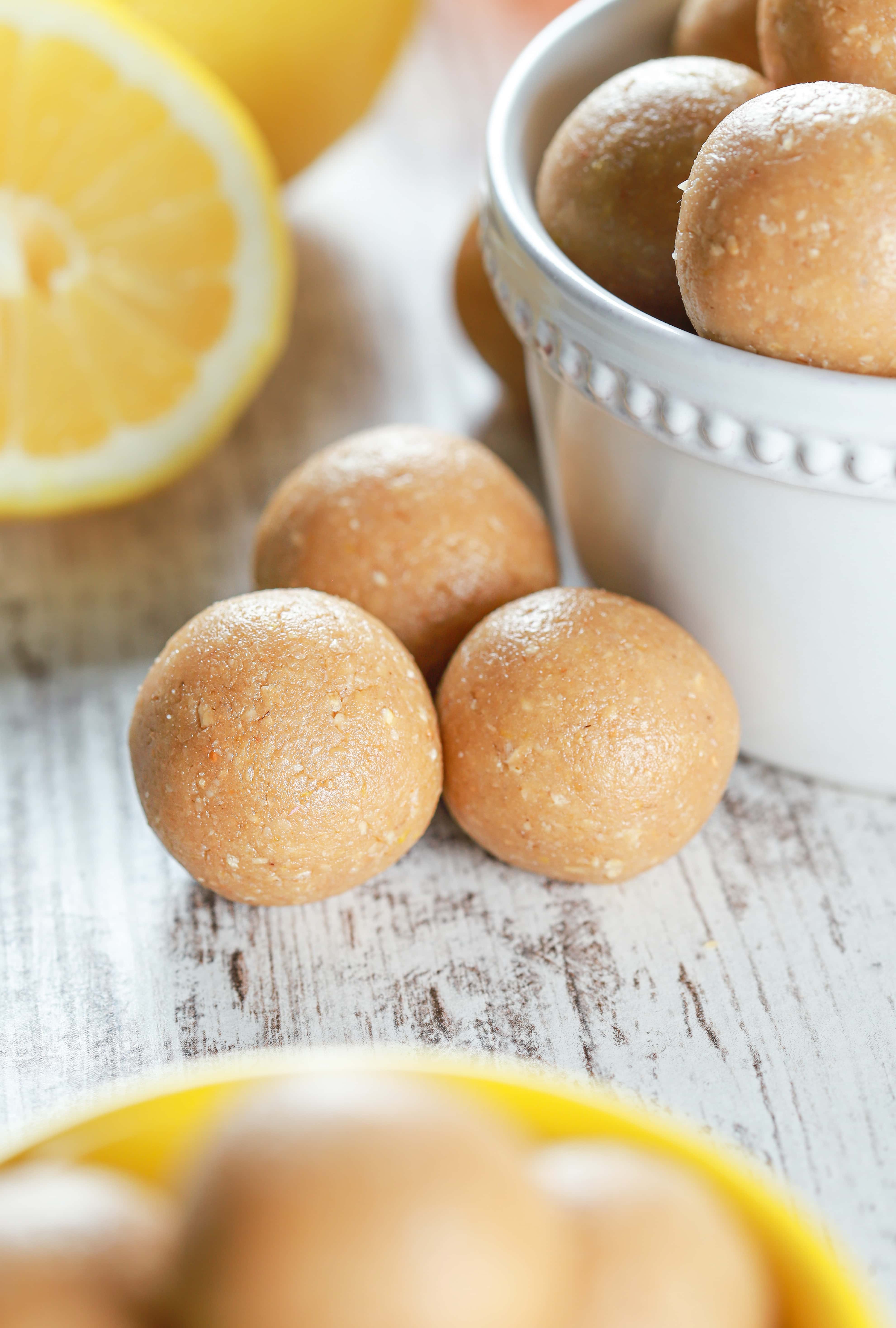 Up close image of three Lemon Protein Bites with lemon halves in the background. Recipe for bites from A Kitchen Addiction