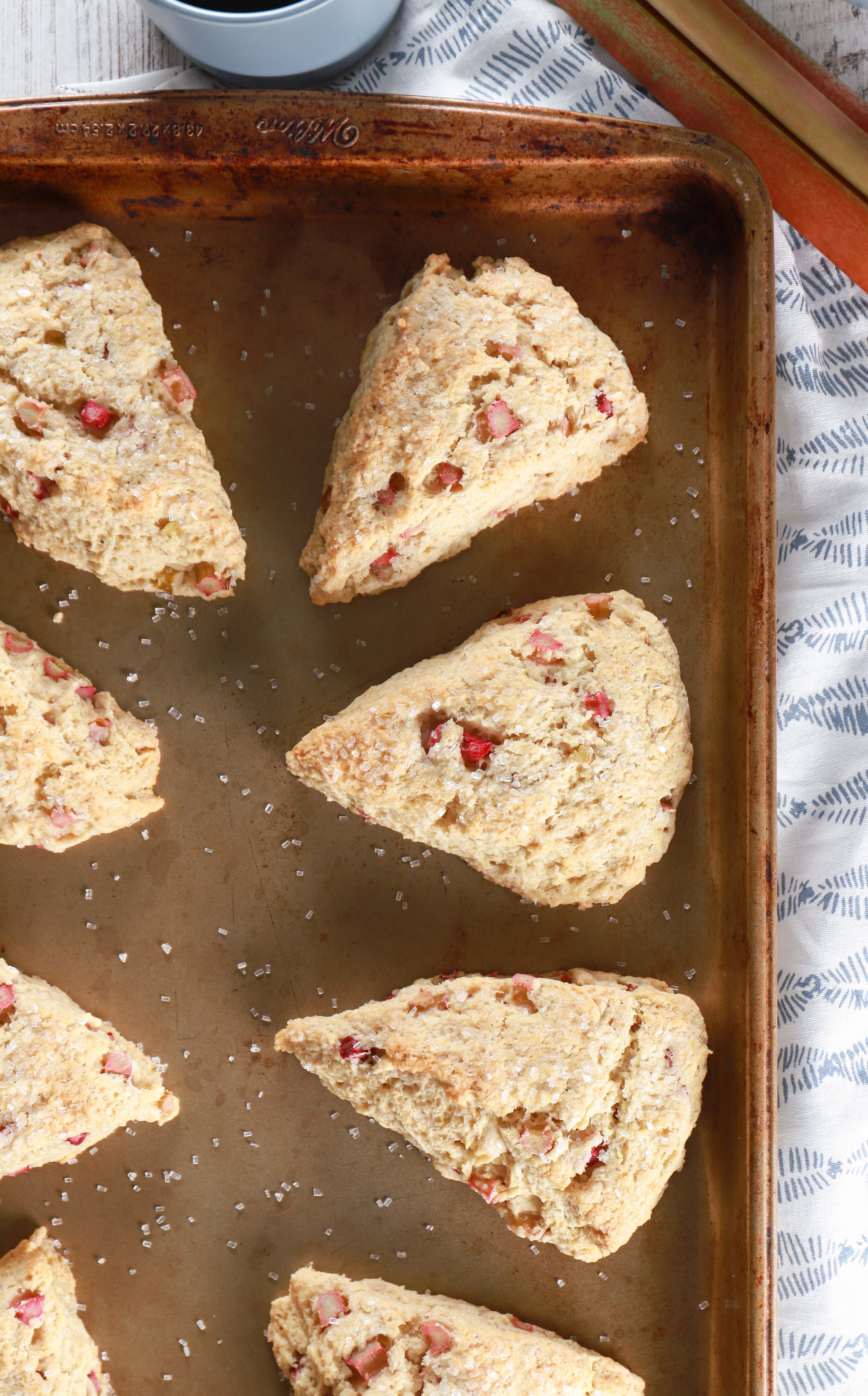 Overhead view of a batch of rhubarb scones on a baking sheet sitting on a towel. Recipe from A Kitchen Addiction