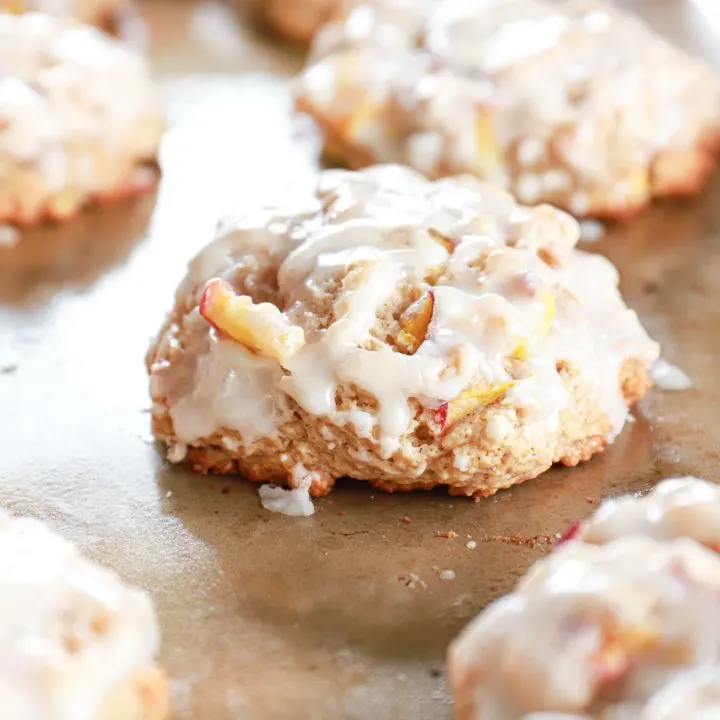 Up close view of glazed baked peach fritters on a cookie sheet.