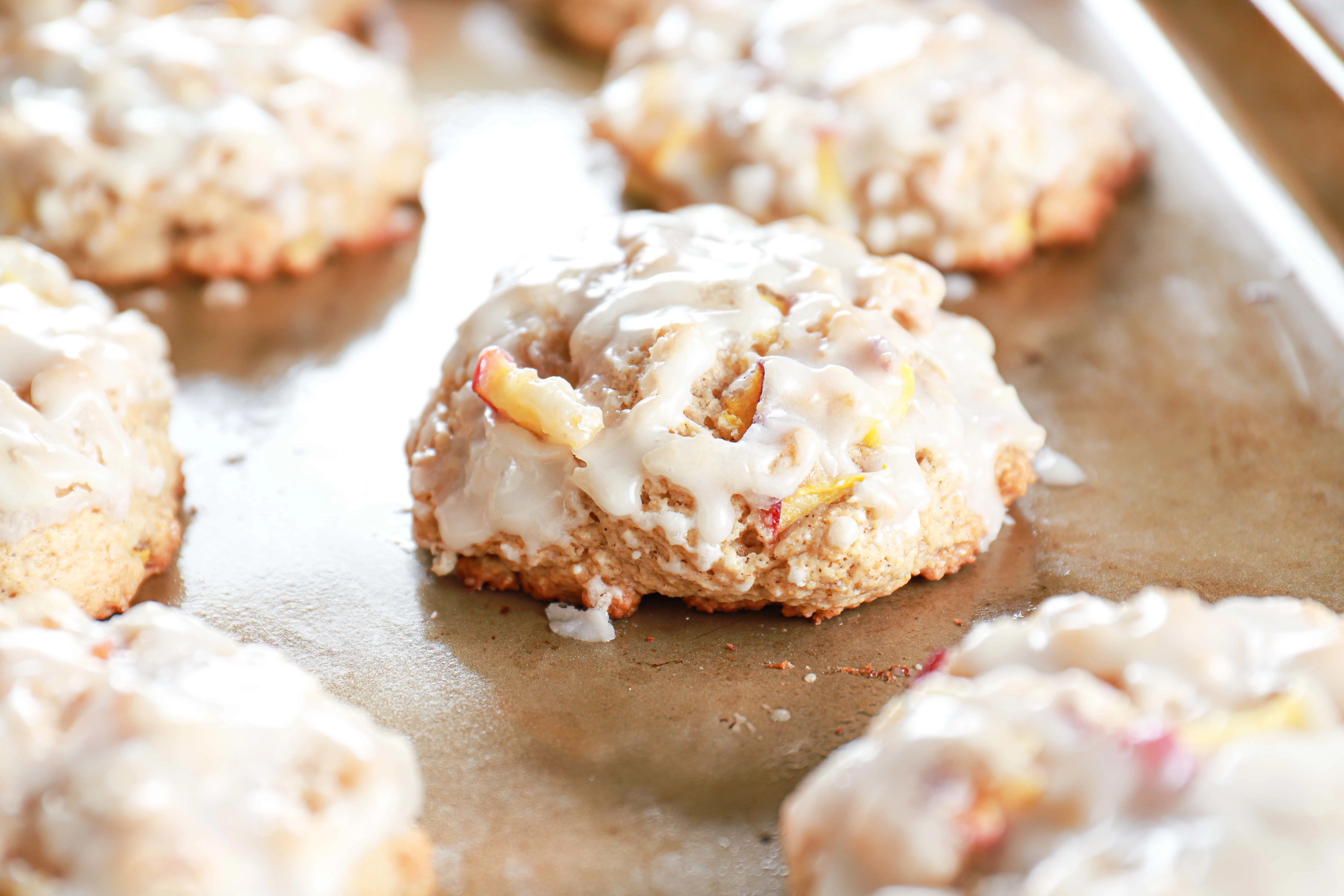 Up close view of glazed baked peach fritters on a cookie sheet.