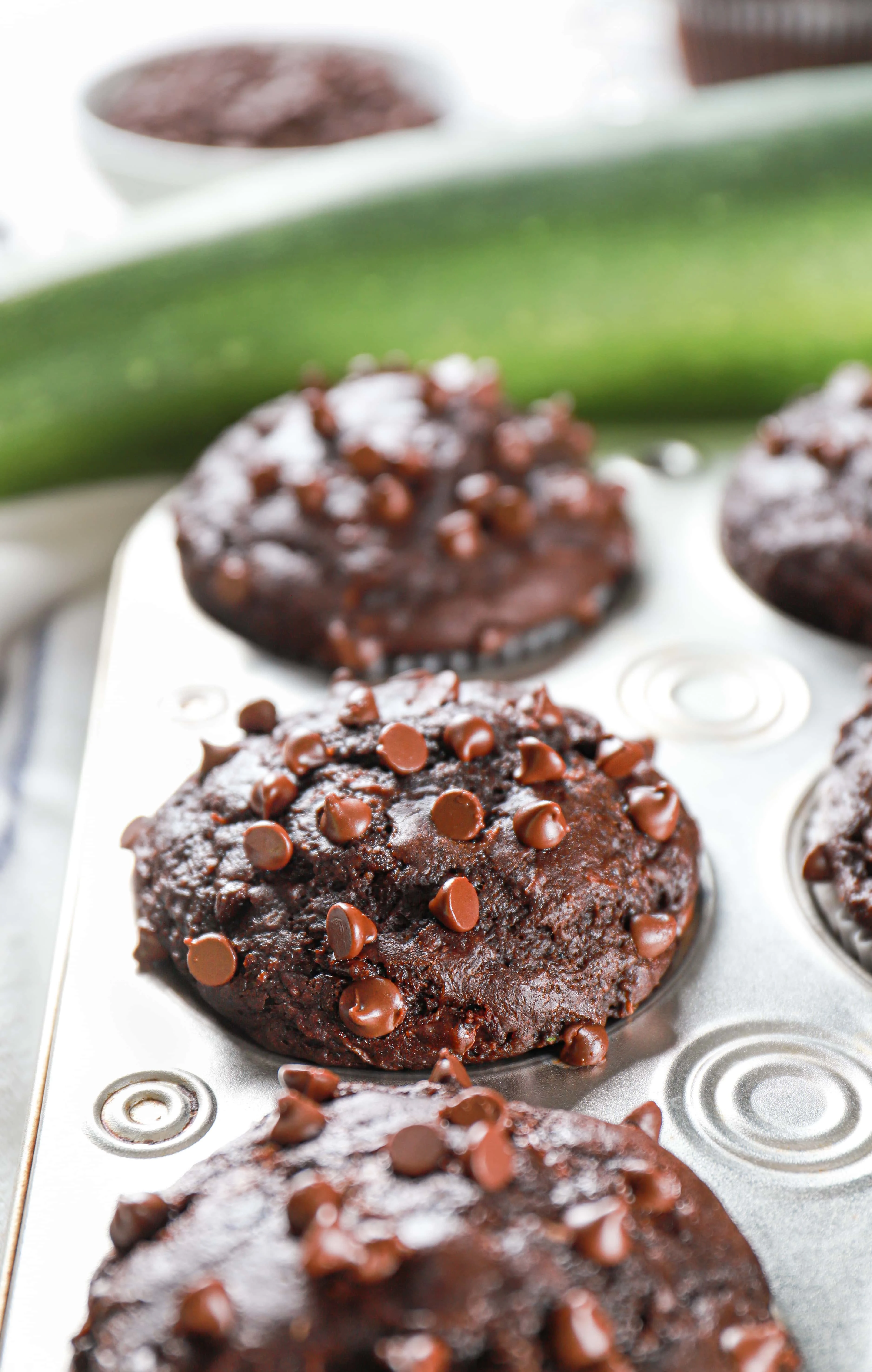 Double chocolate zucchini muffins topped with mini chocolate chips in a muffin tin