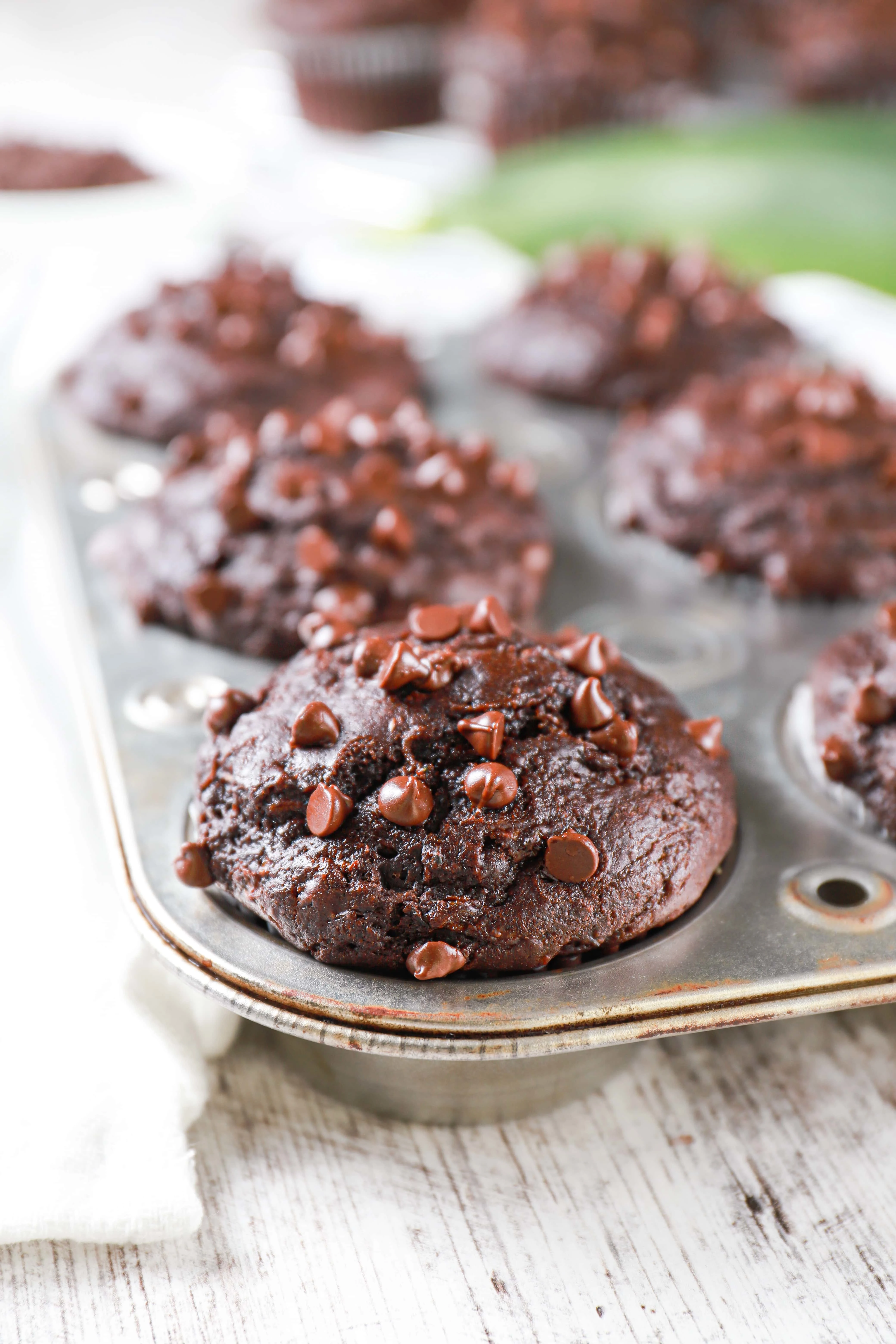 Up close view of a double chocolate chip zucchini muffin in a muffin tin