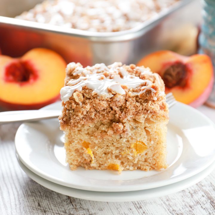 Up close side view of a piece of peach coffee cake on a small white plate.