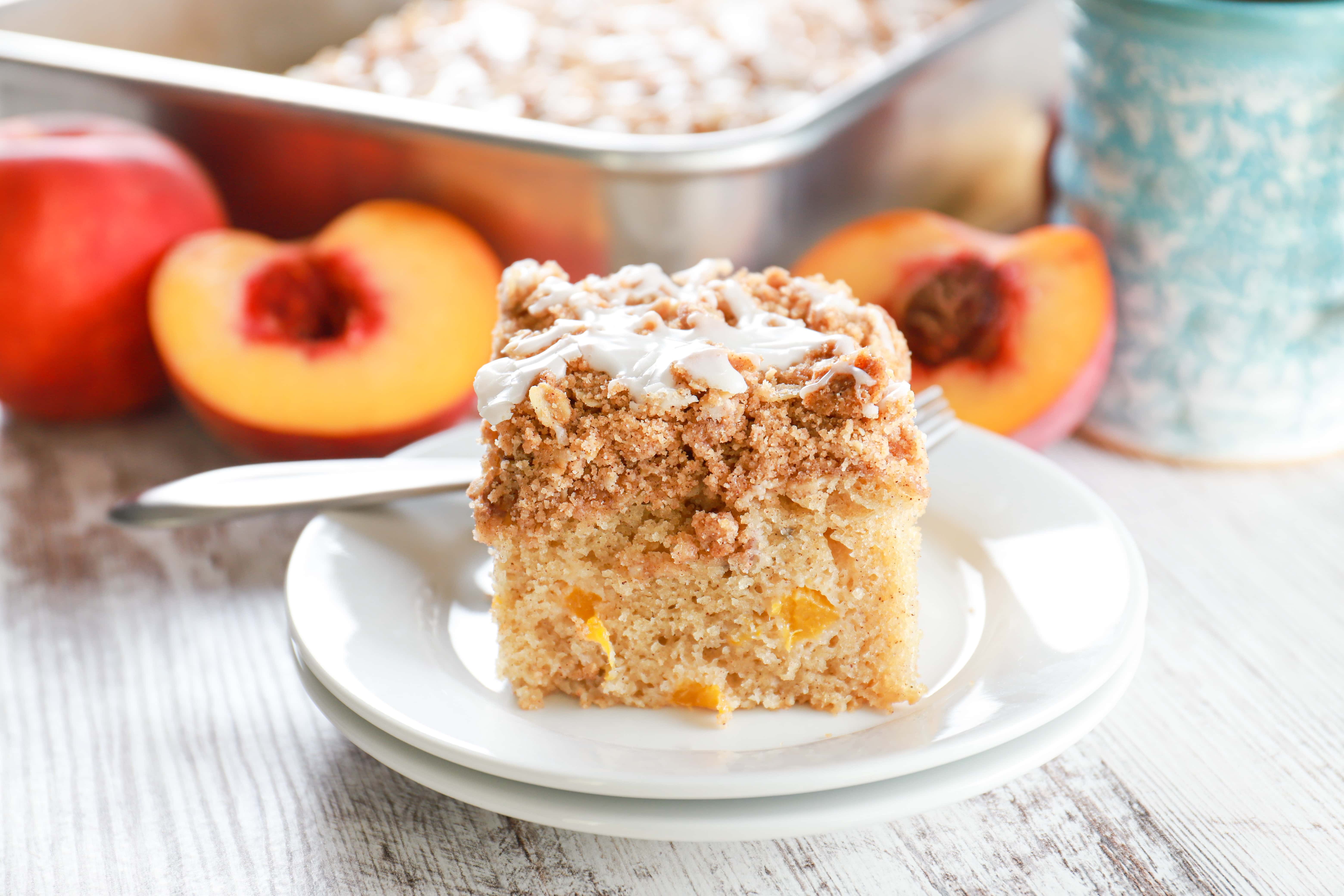 Up close side view of a piece of peach coffee cake on a small white plate.