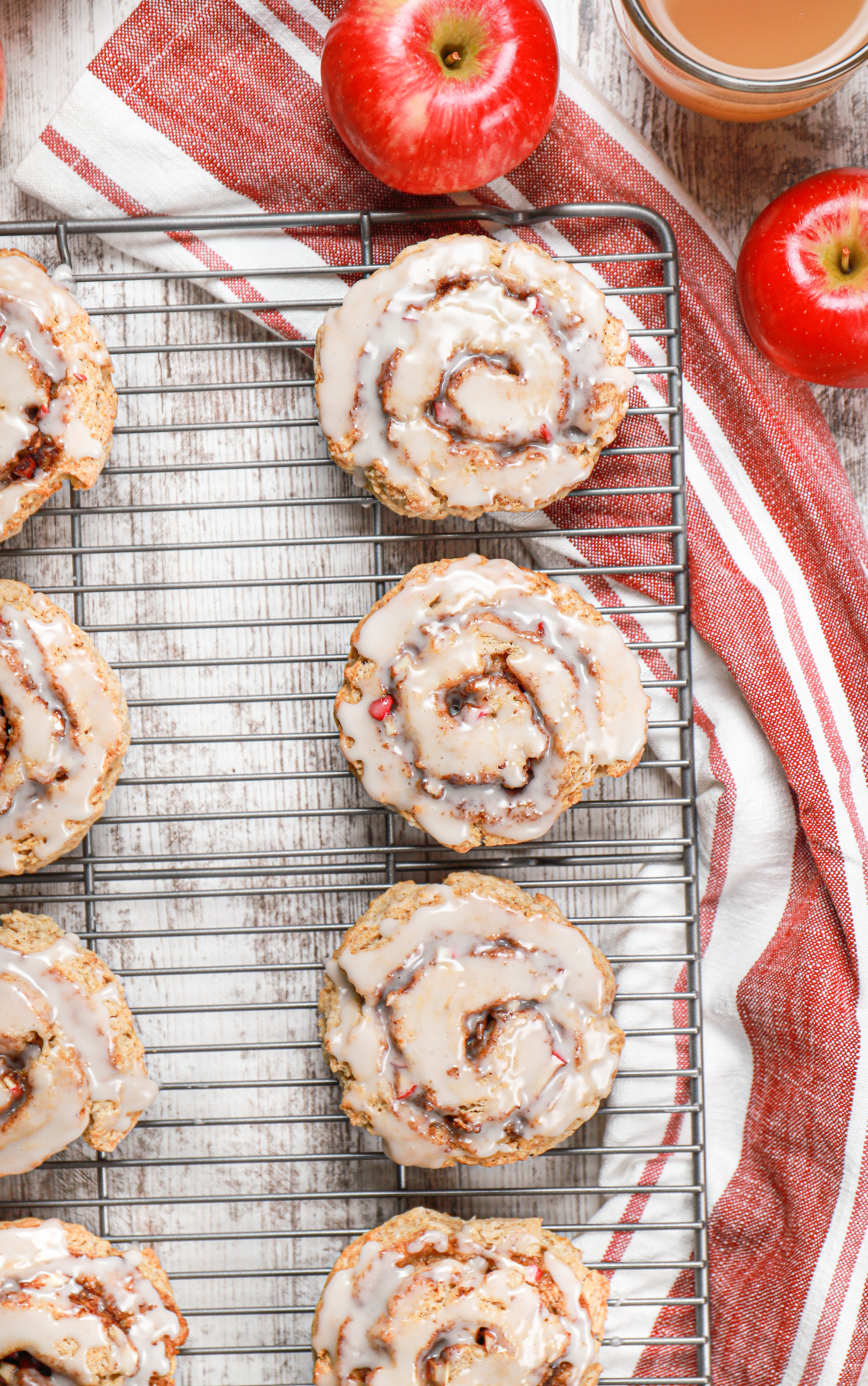 Overhead view of a batch of glazed apple cinnamon roll scones on a cooling rack