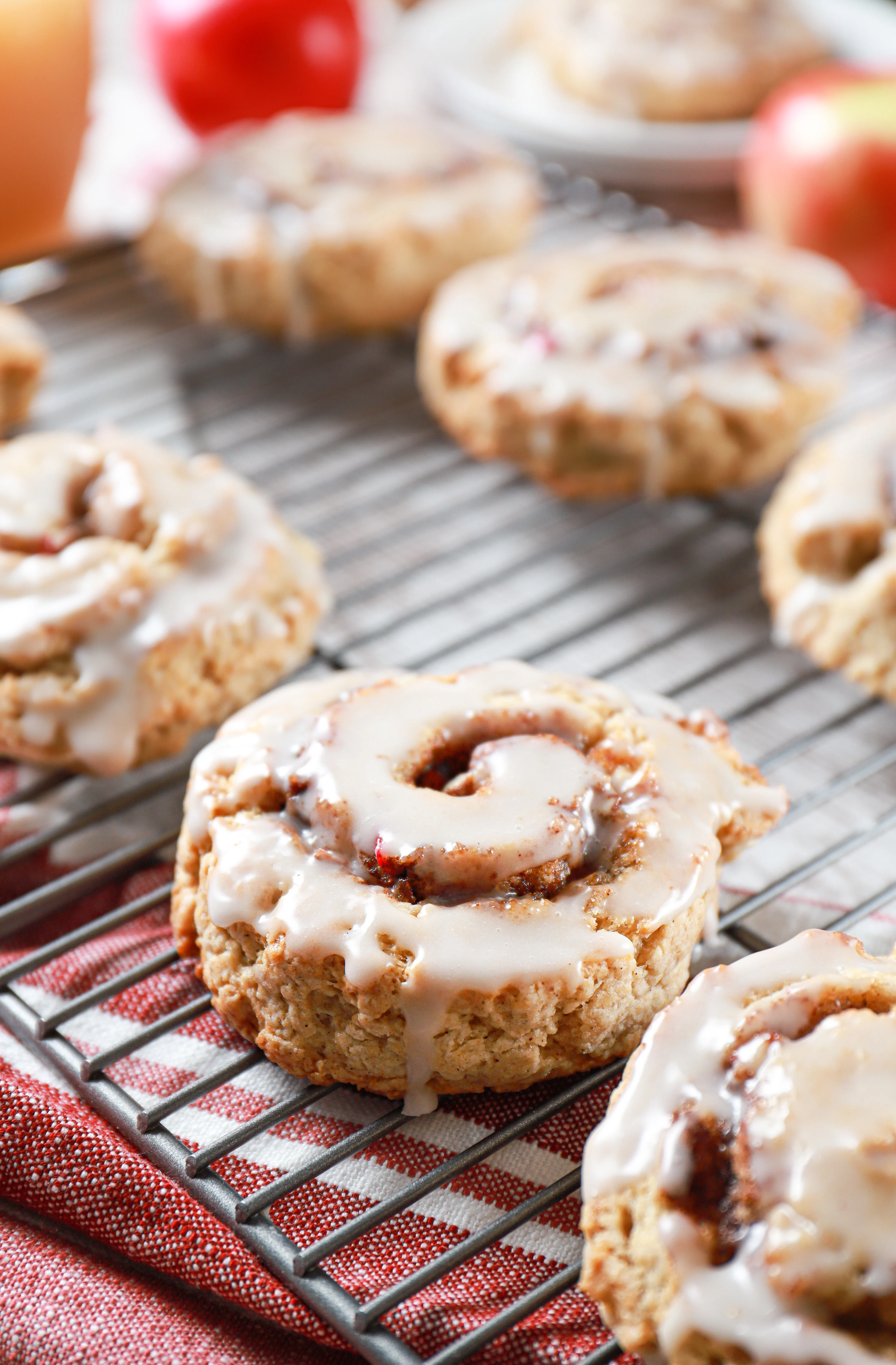 Up close side view of an apple cinnamon roll scone on a cooling rack with more scones in the background