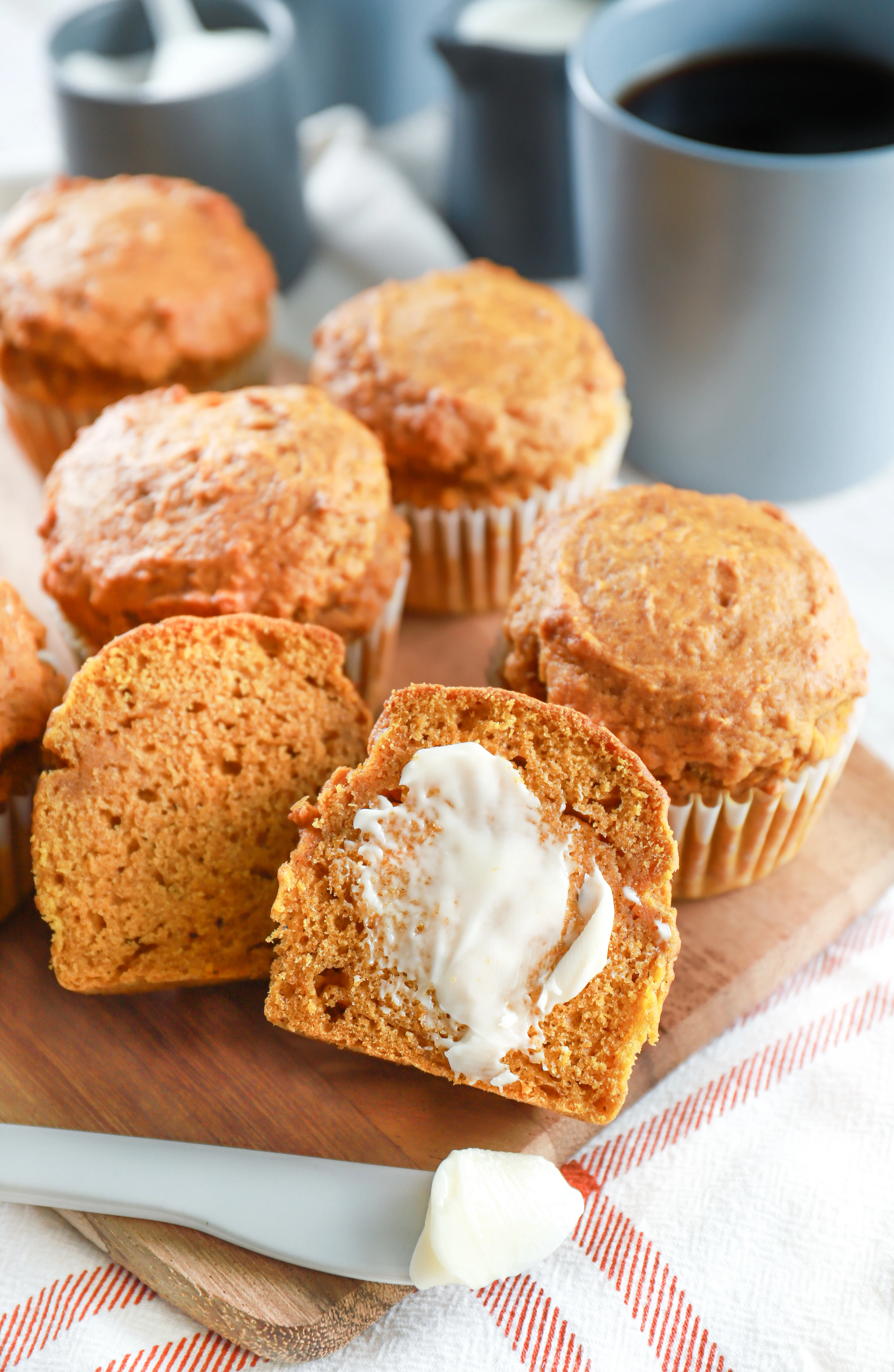 A pumpkin muffin sliced open and buttered on a wooden cutting board