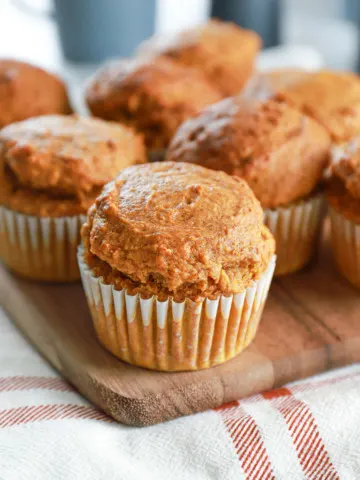 Up close view of a bakery style pumpkin muffin on a wooden cutting board