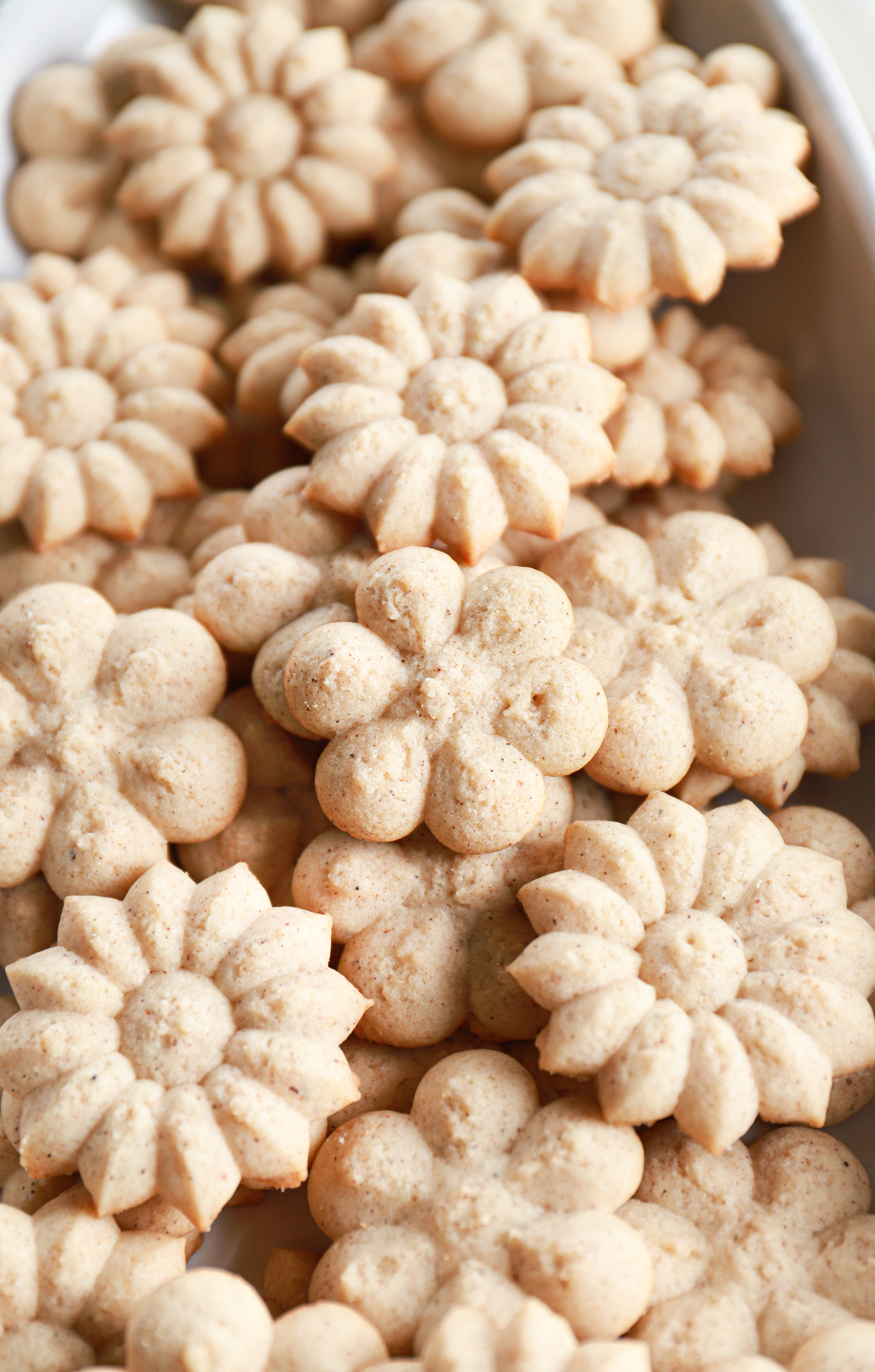 Up close angle view of a platter full of chai spiced spritz cookies. Recipe for cookies from A Kitchen Addiction