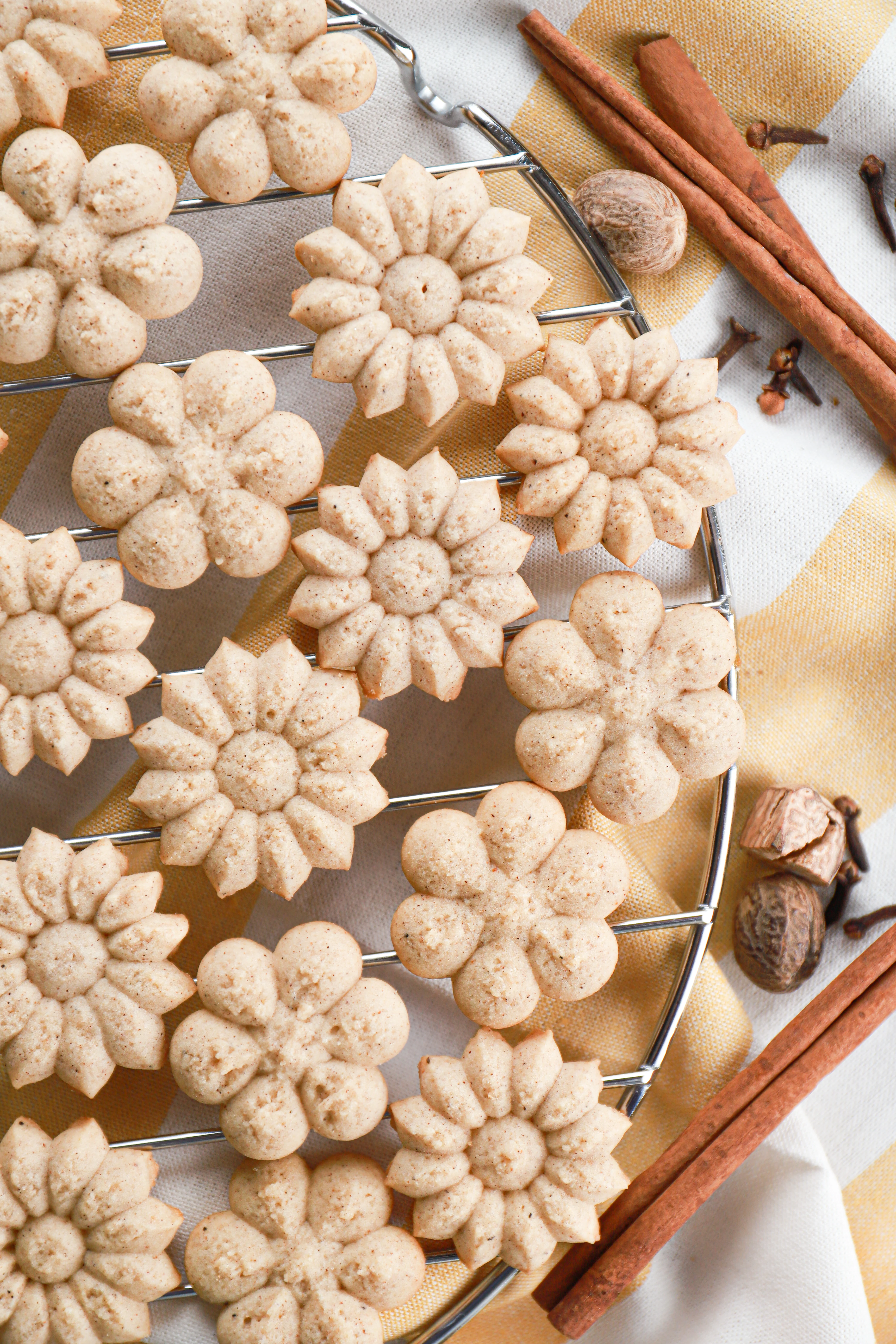 A batch of chai spritz cookies on a wire cooling rack. Recipe for cookies from A Kitchen Addiction