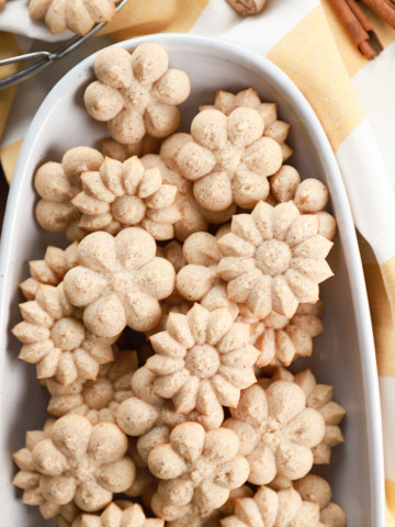 Above view of a batch of chai spice spritz cookies on an oblong white platter