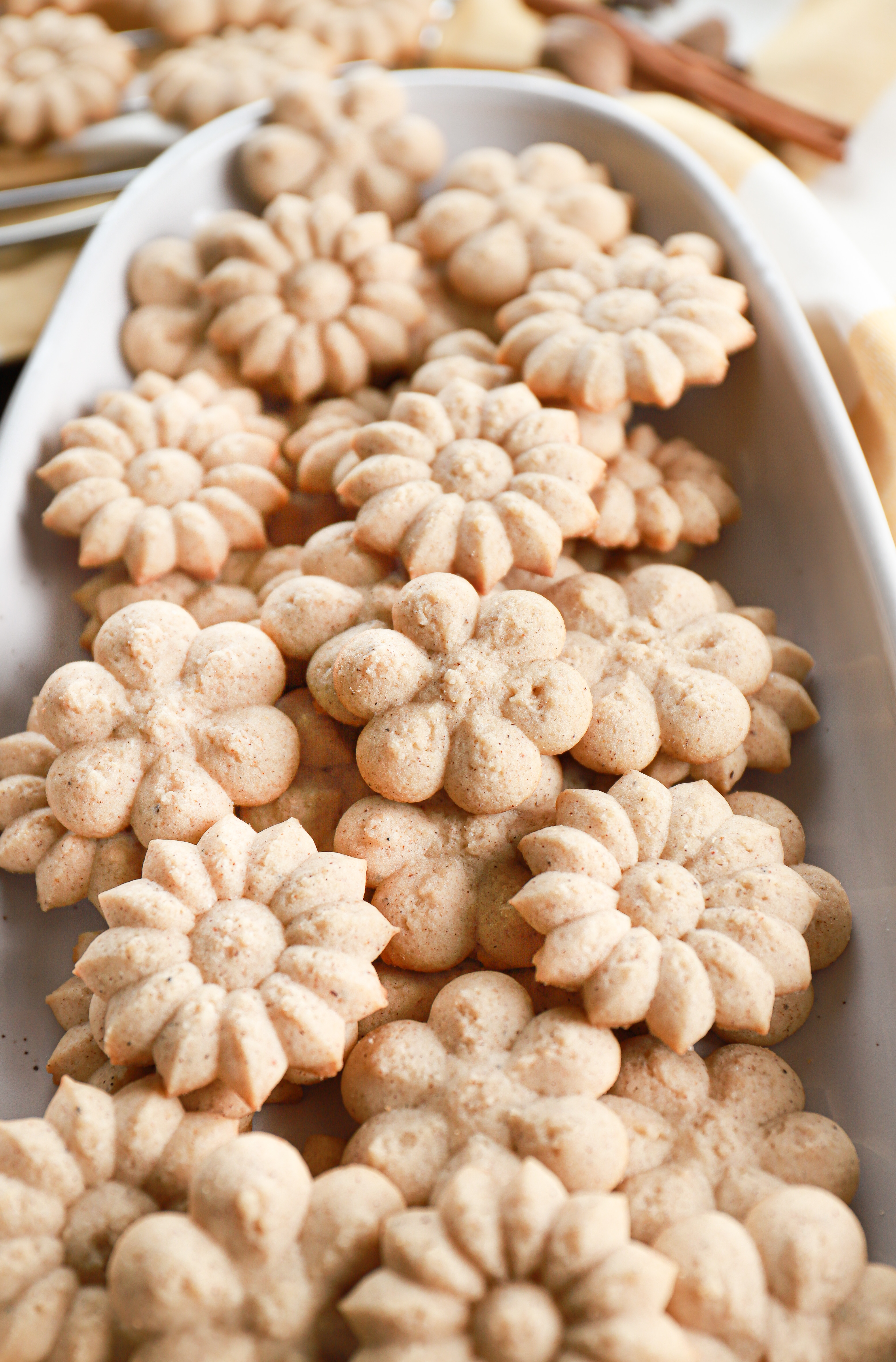 Up close view of a batch of chai spritz cookies on an oblong white platter