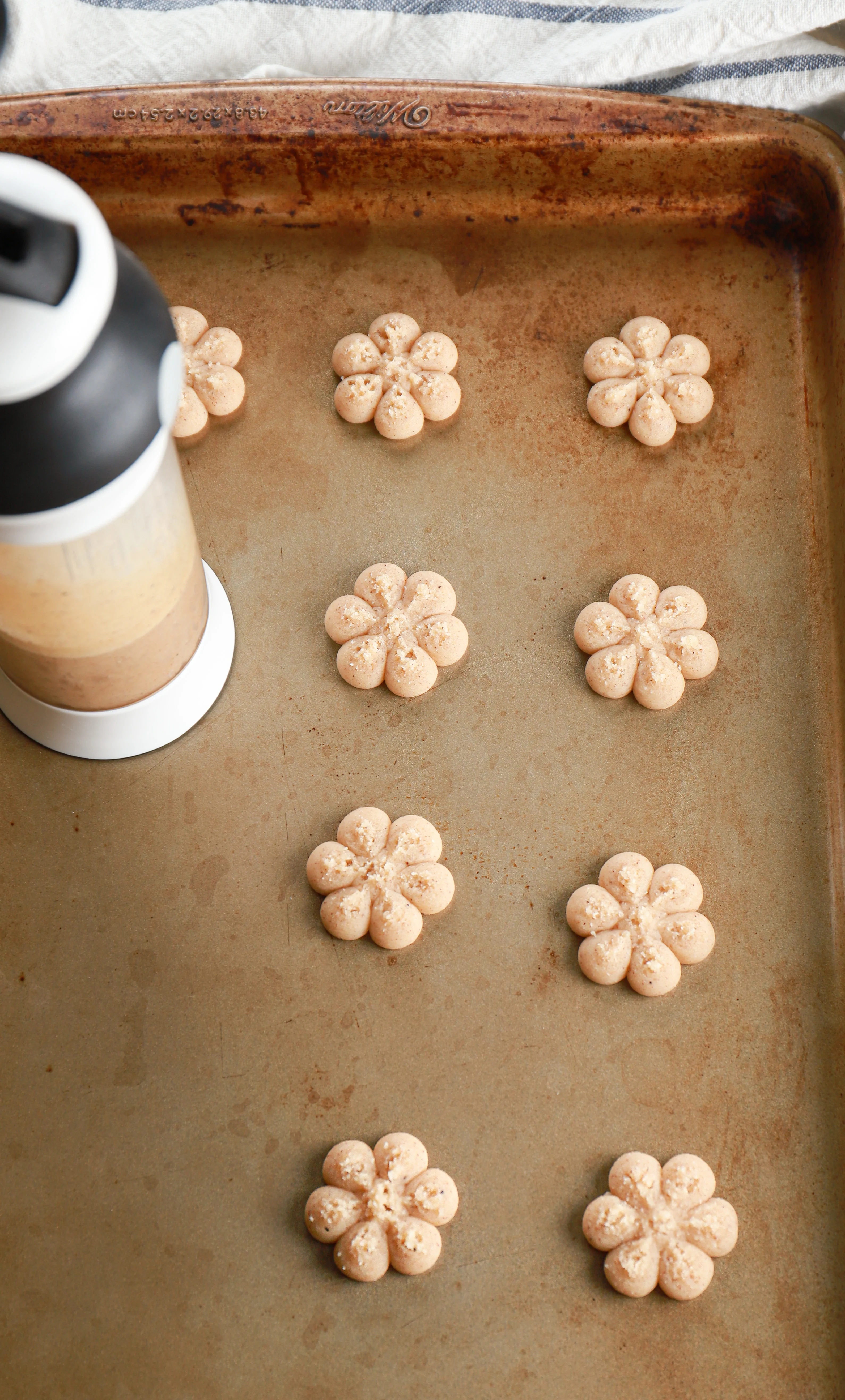 cookie press with pressed dough on a cookie sheet