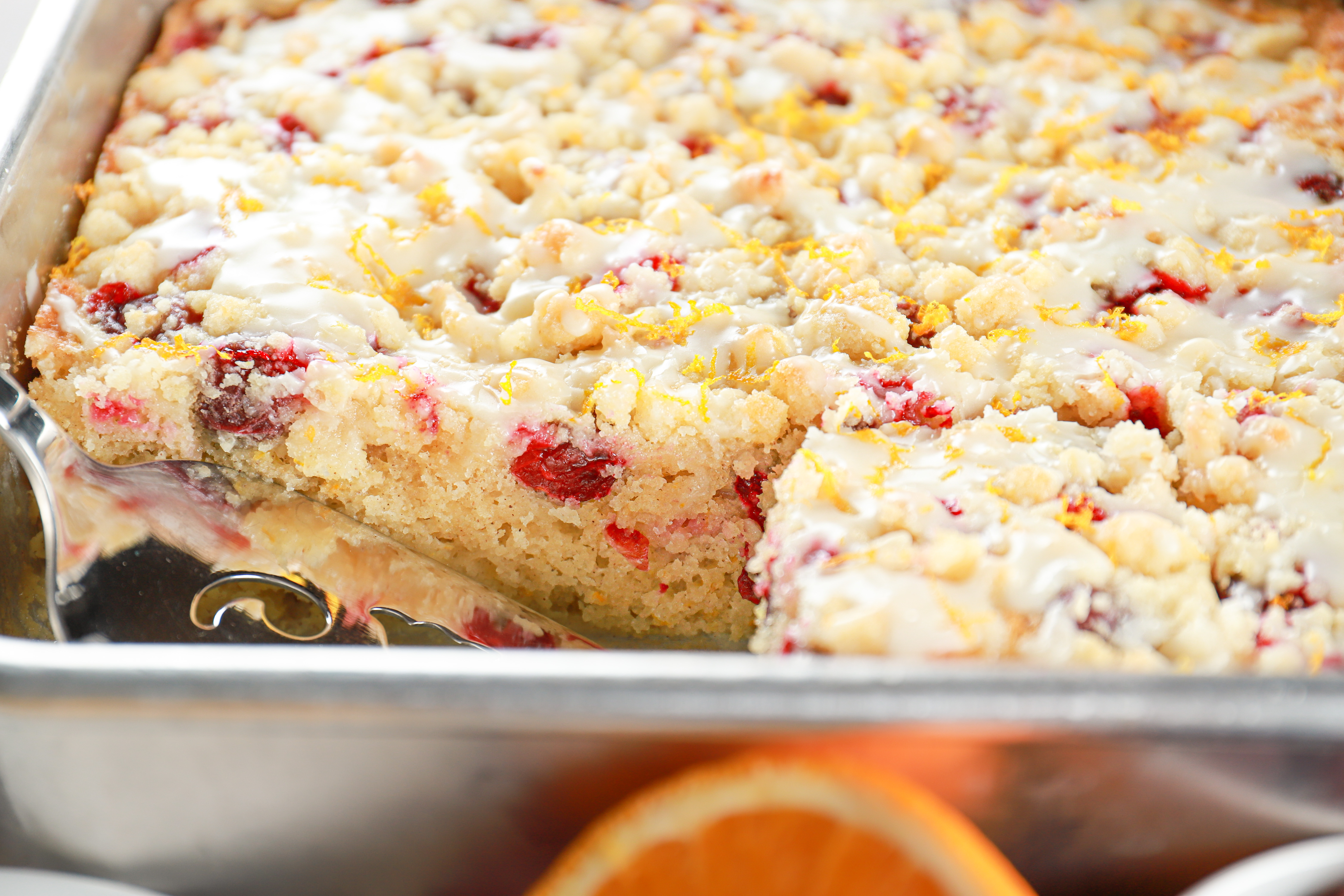 Side view of a cranberry orange crumb cake with a piece taken out. Recipe from A Kitchen Addiction