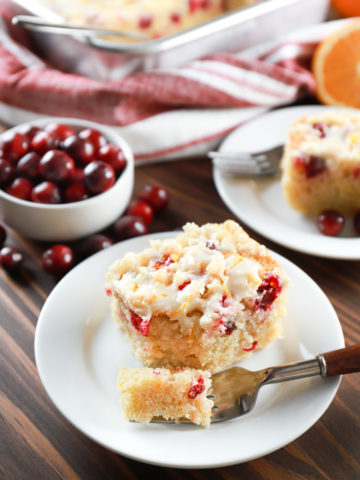 Two pieces of cranberry orange coffee cake on small white plates. Recipe from A Kitchen Addiction