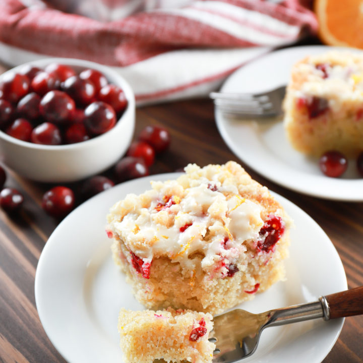 Two pieces of cranberry orange coffee cake on small white plates. Recipe from A Kitchen Addiction