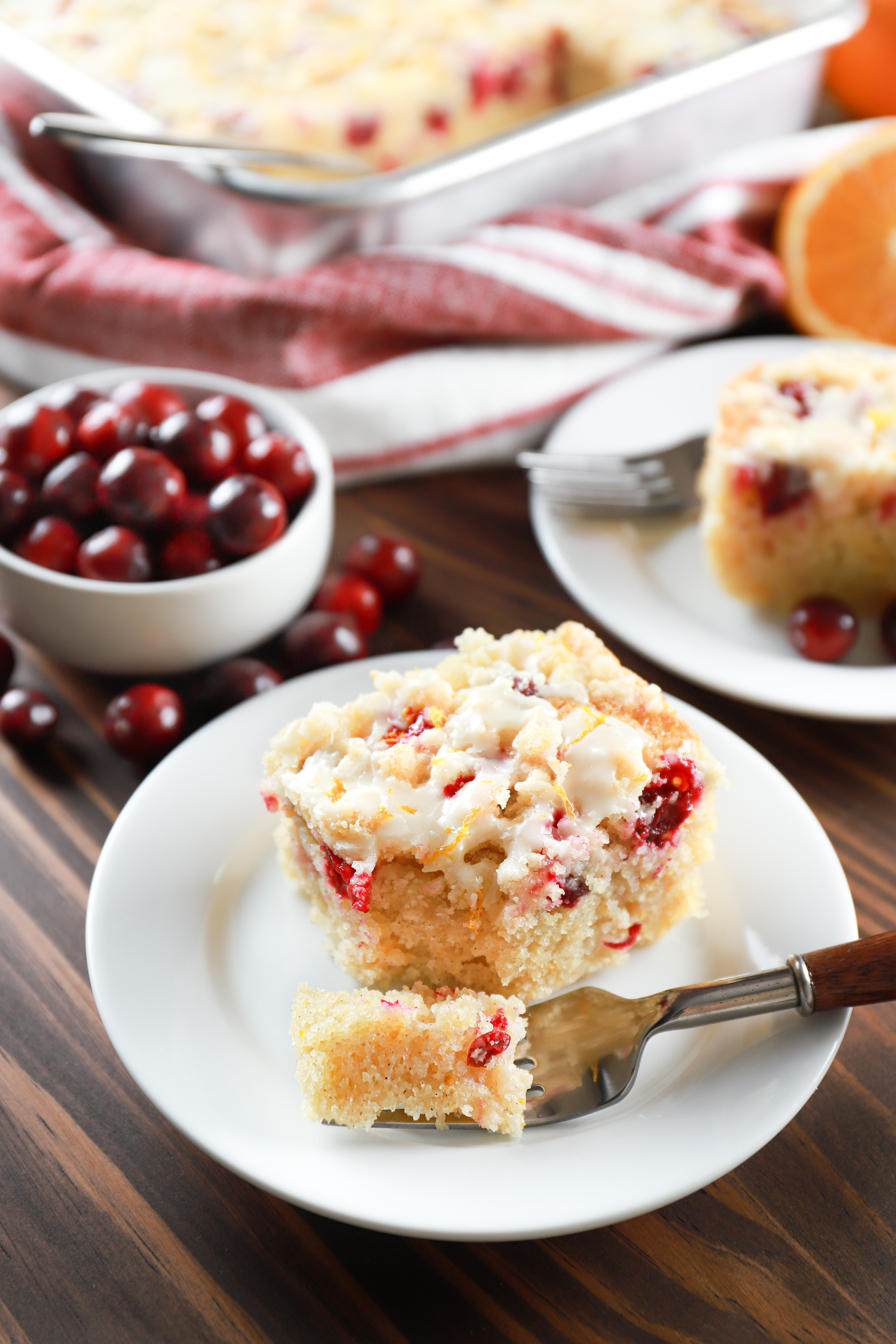 Two pieces of cranberry orange coffee cake on small white plates. Recipe from A Kitchen Addiction