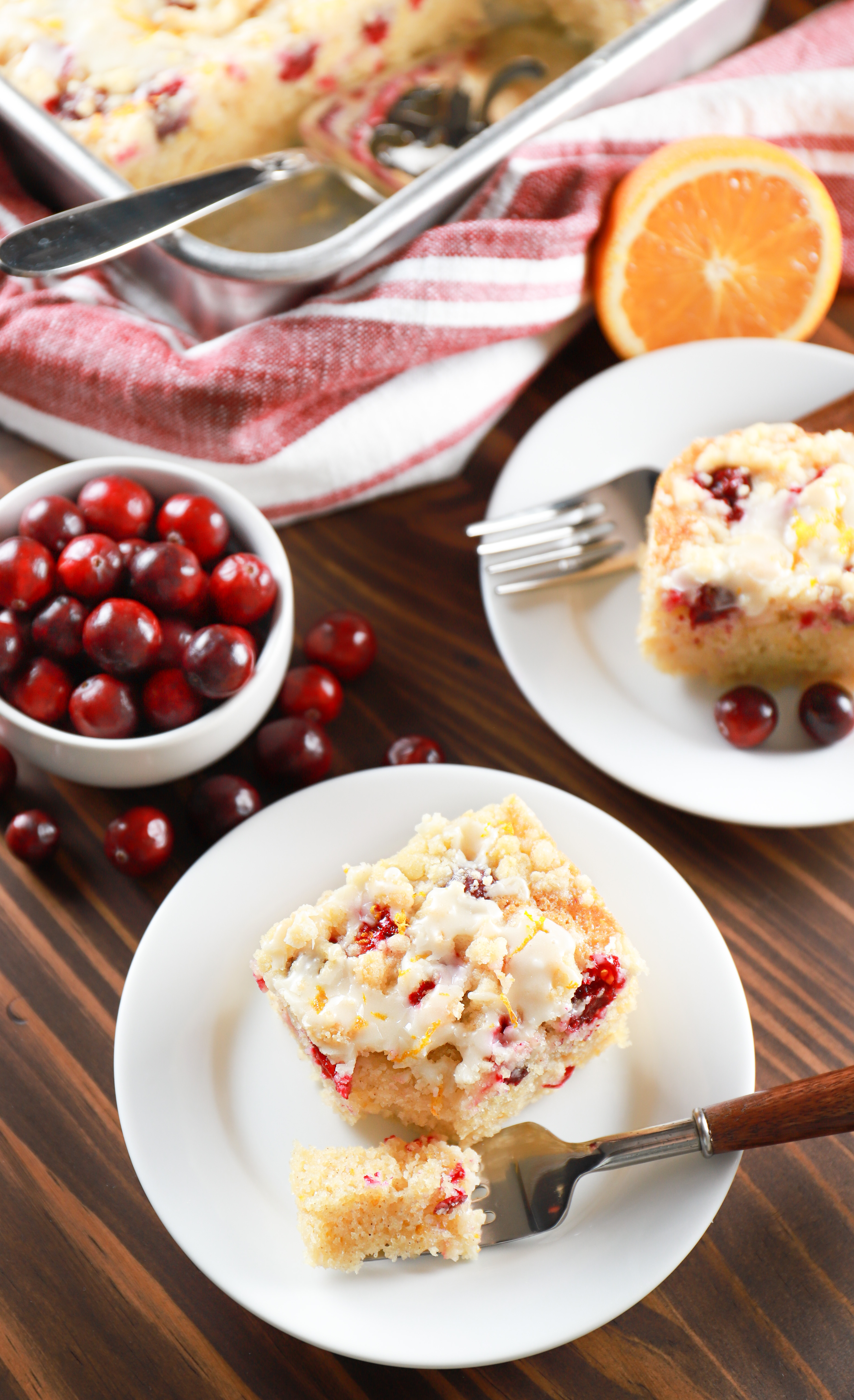 Overhead view of two pieces of cranberry orange coffee cake on small white plates.