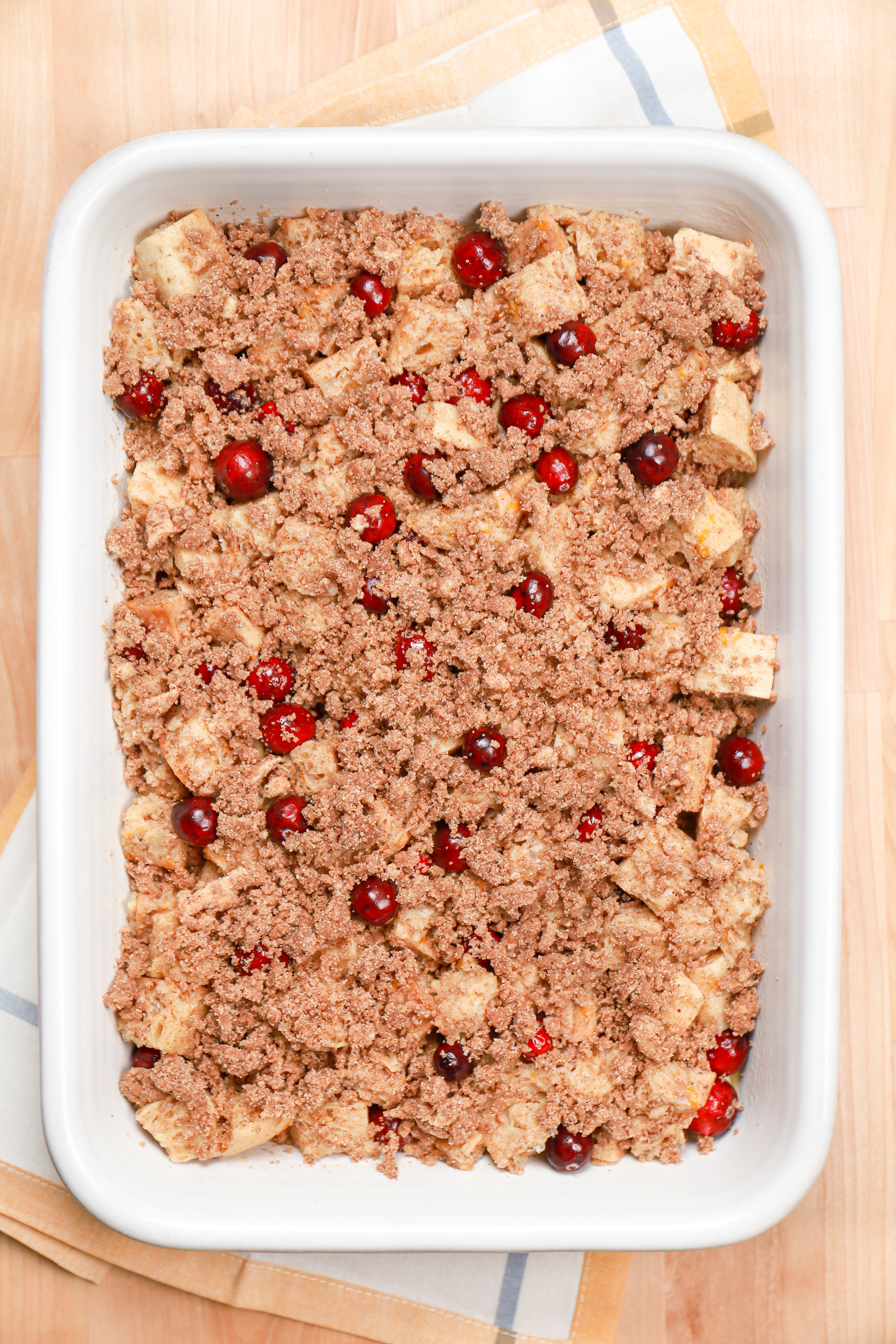 Cranberry orange french toast bake in a white casserole dish right before baknig.