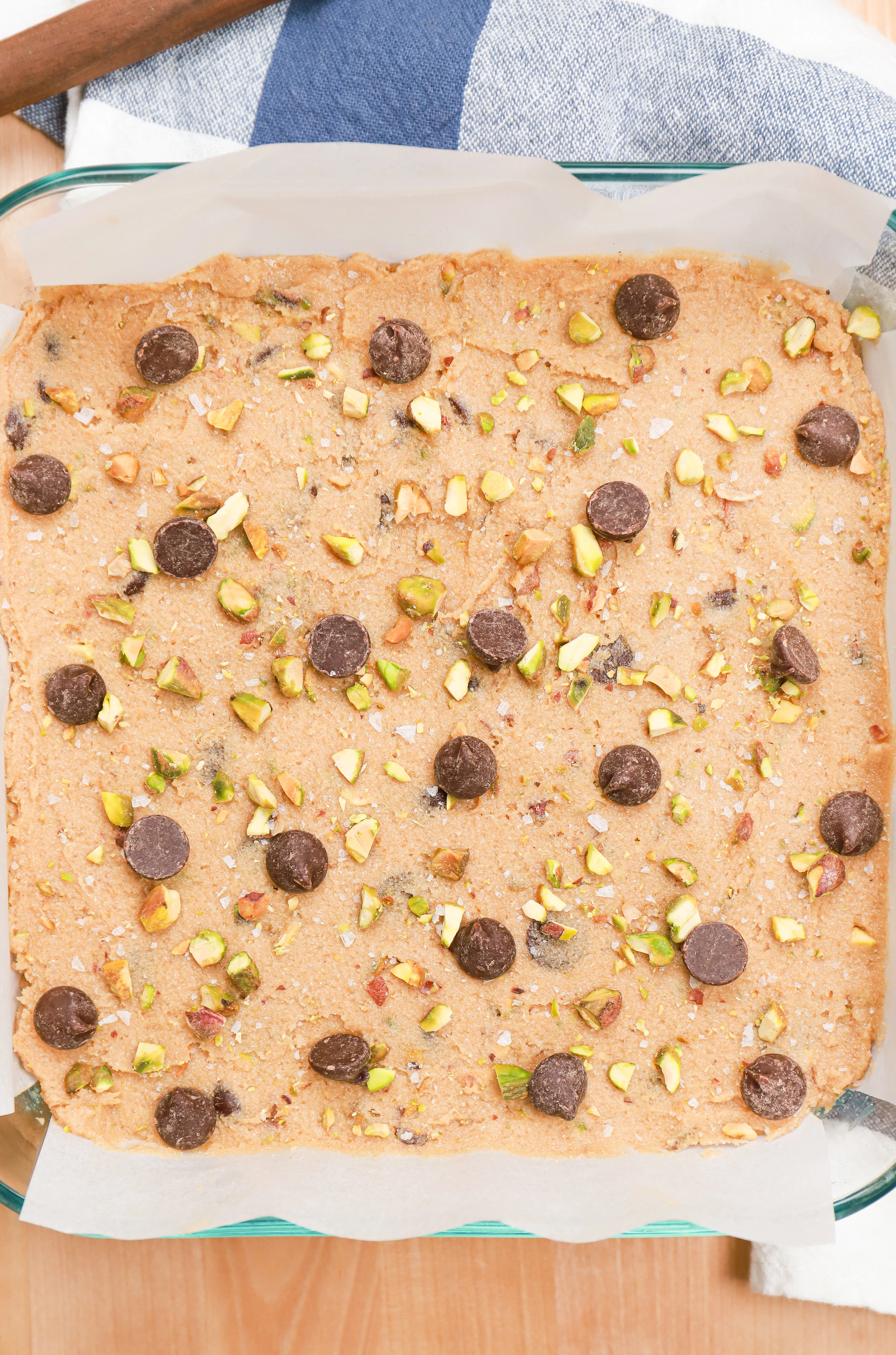 Overhead view of salted dark chocolate pistachio cookie bars dough in pan before baking.