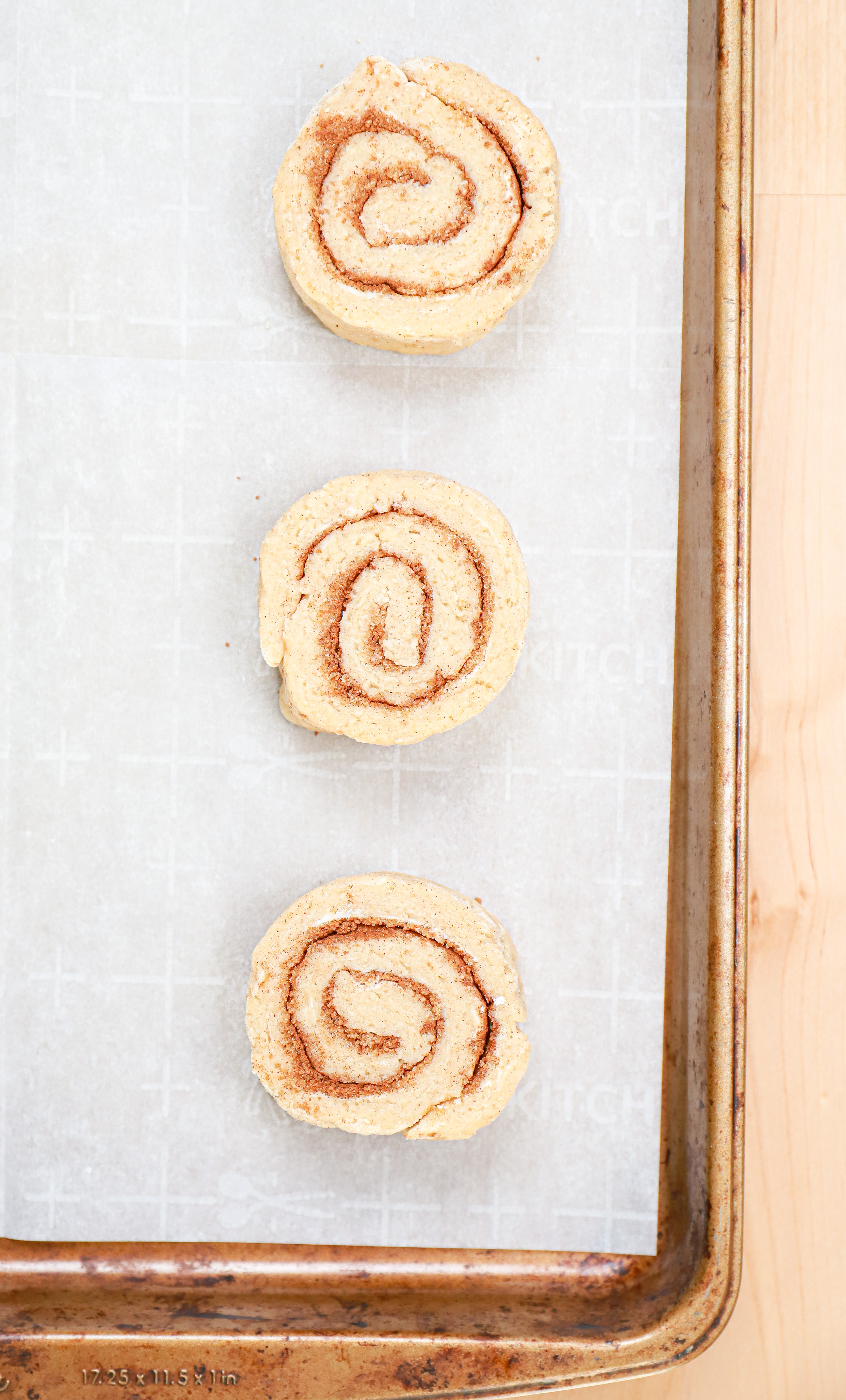 Cinnamon roll scone dough spirals on a parchment paper lined baking sheet.