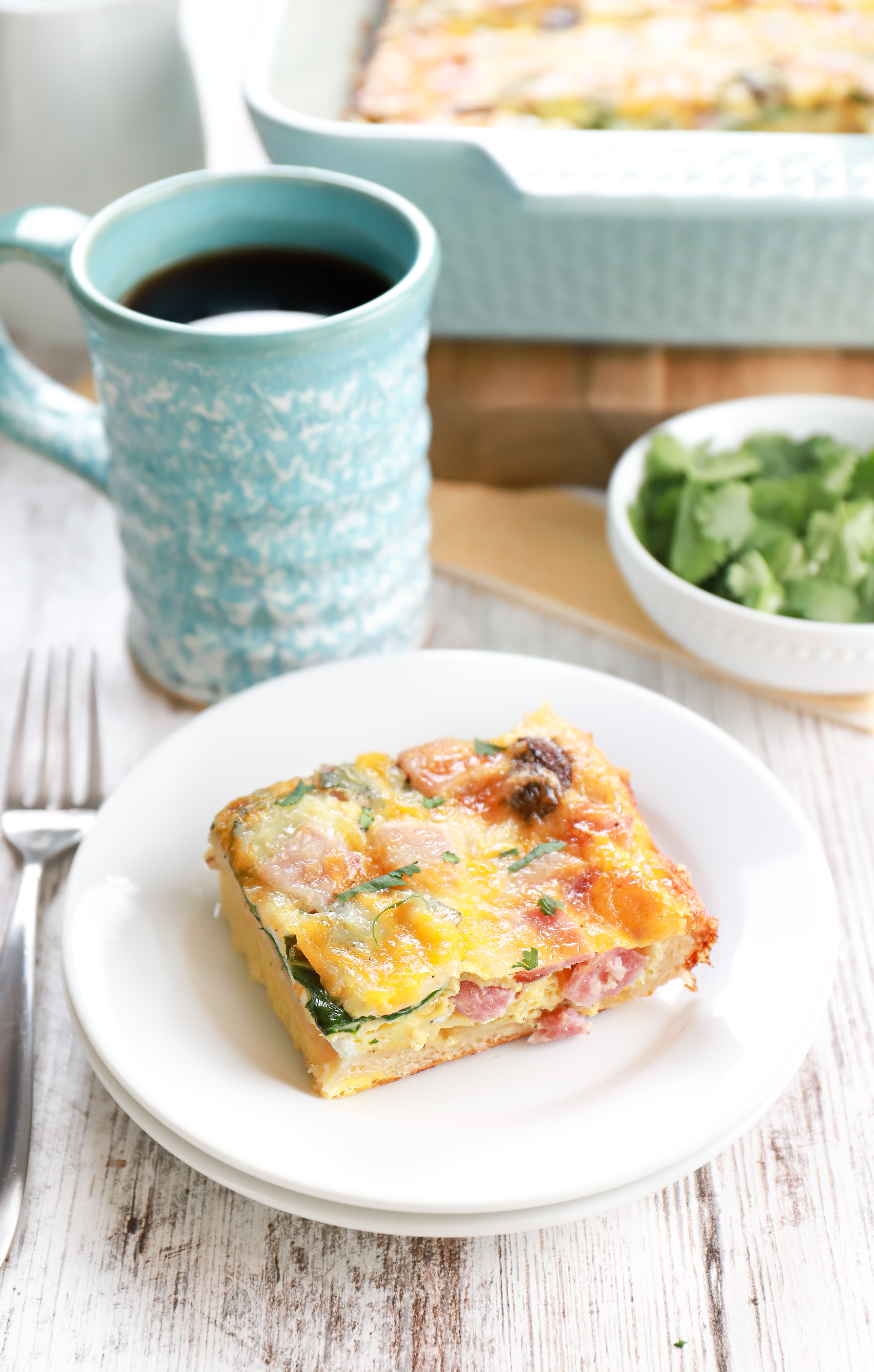 A slice of cheesy ham crescent roll breakfast casserole on a small white plate.