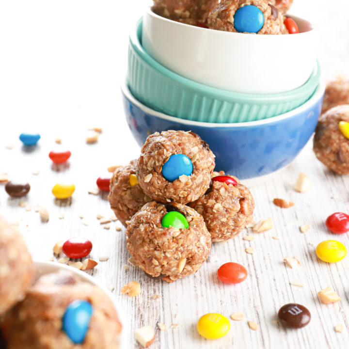 Side view of a cluster of almond butter trail mix bites against a stack of small bowls.