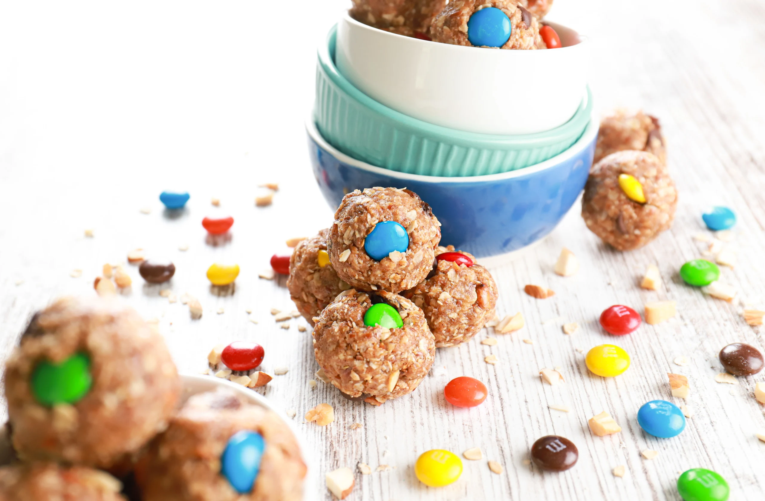 Side view of a cluster of almond butter trail mix bites against a stack of small bowls.