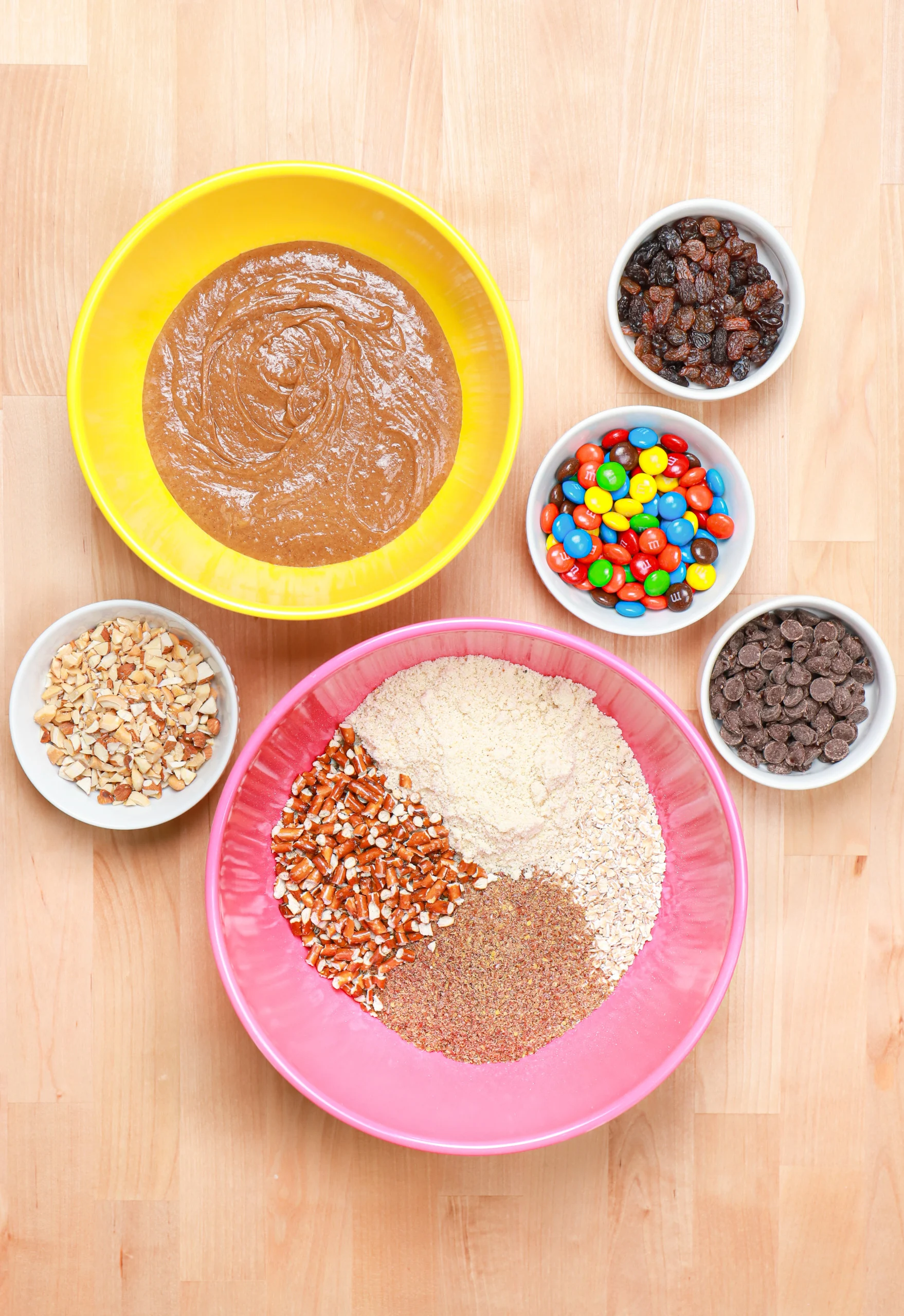 Overhead view of the ingredients for almond butter trail mix bites in various size bowls.