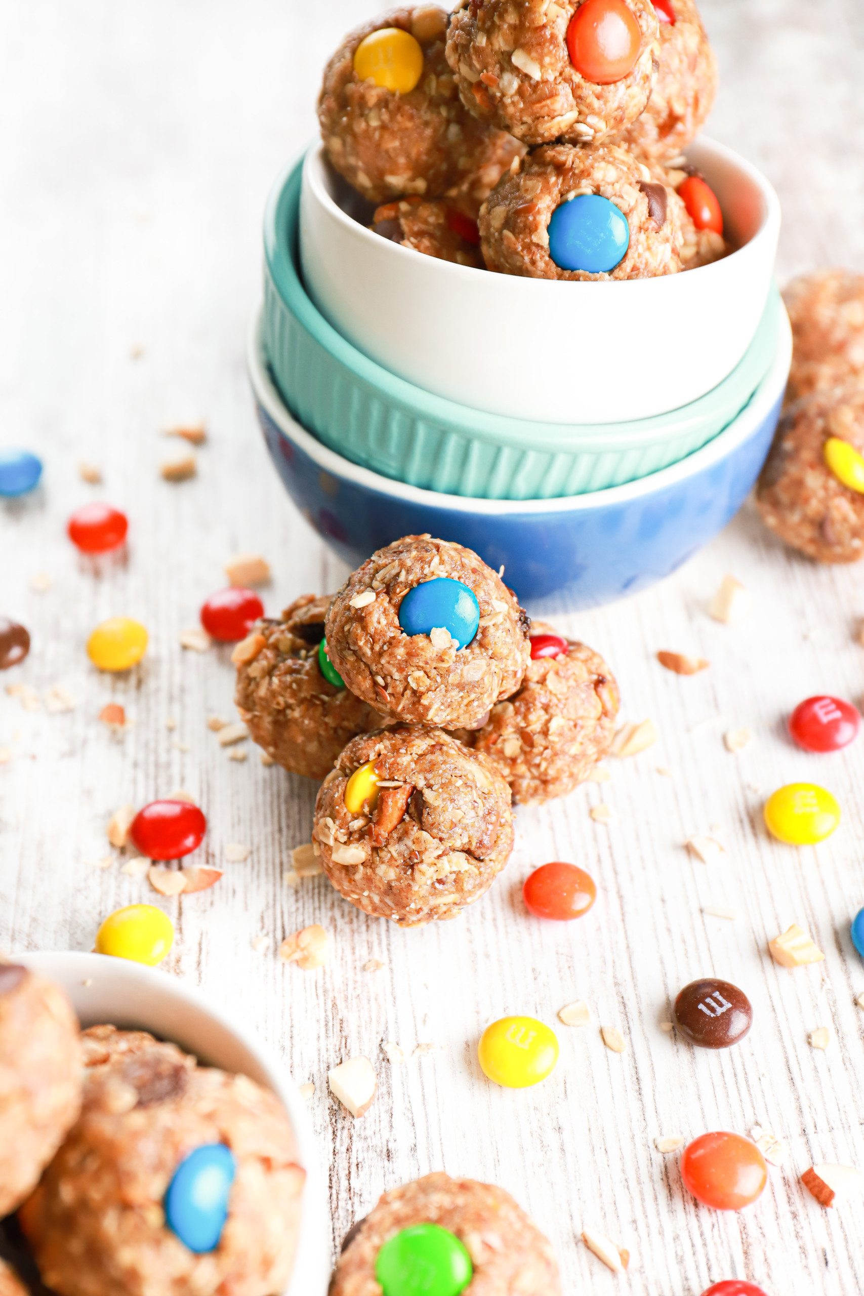 Side view of a cluster of almond butter trail mix bites resting against a stack of small bowls.