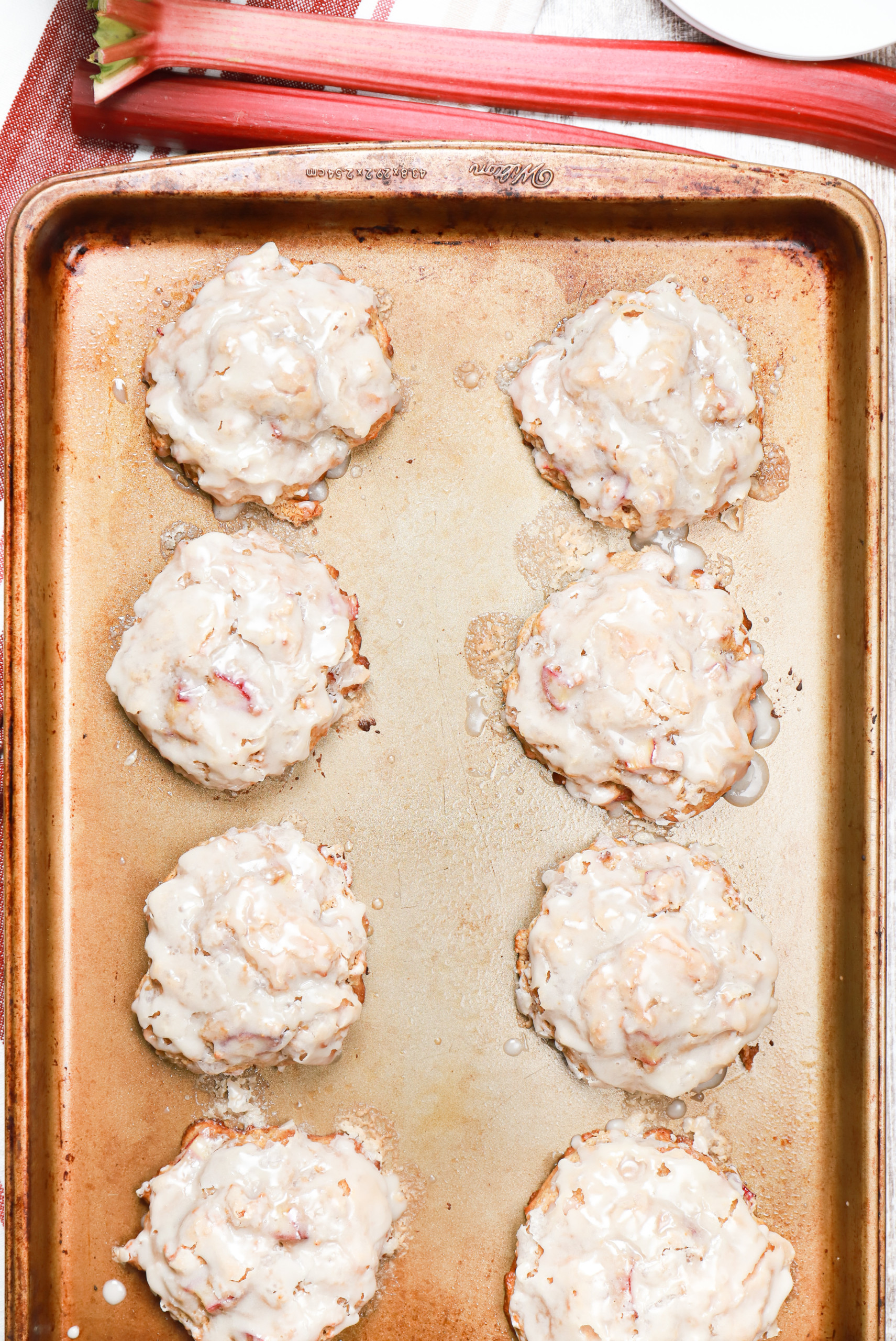 Overhead view of a batch of baked rhubarb fritters on an aluminum baking sheet.
