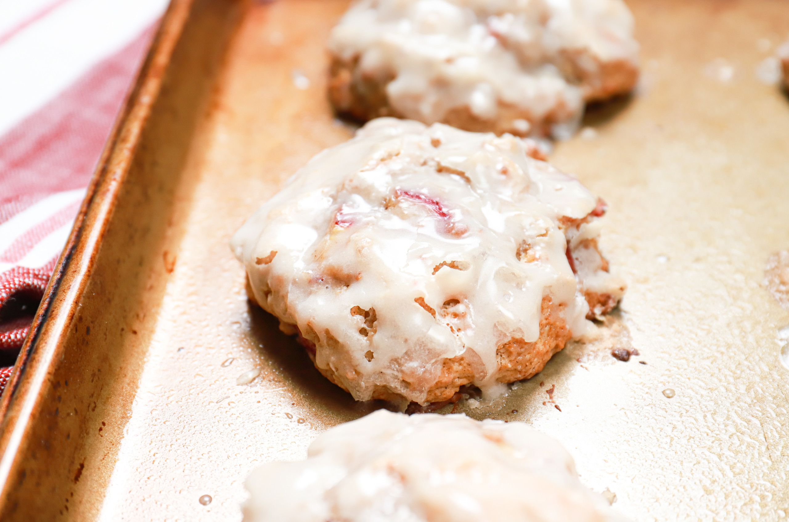 Up close side view of a baked rhubarb fritter on an aluminum baking sheet.