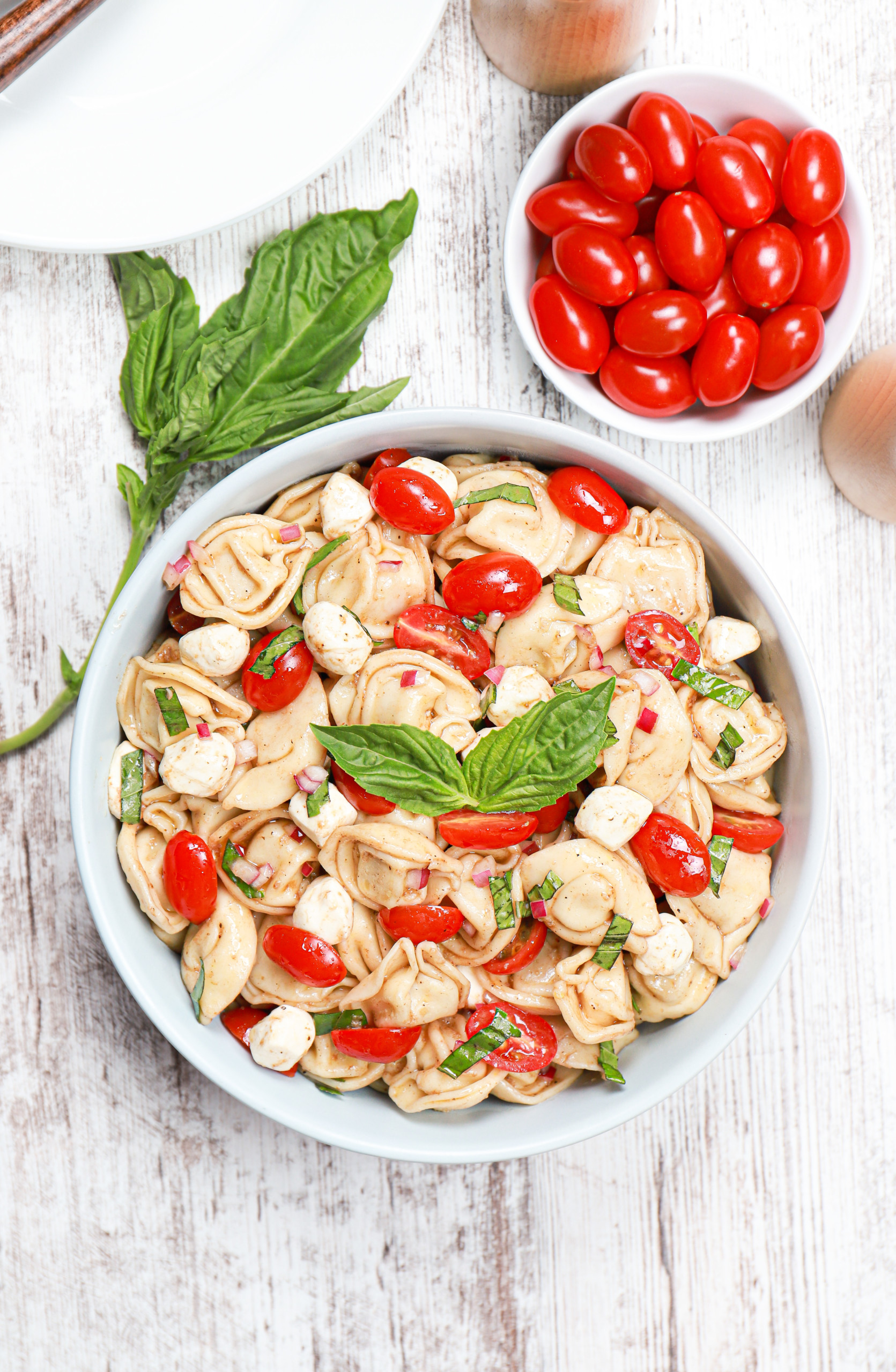 Overhead view of a light blue bowl full of caprese tortellini salad.