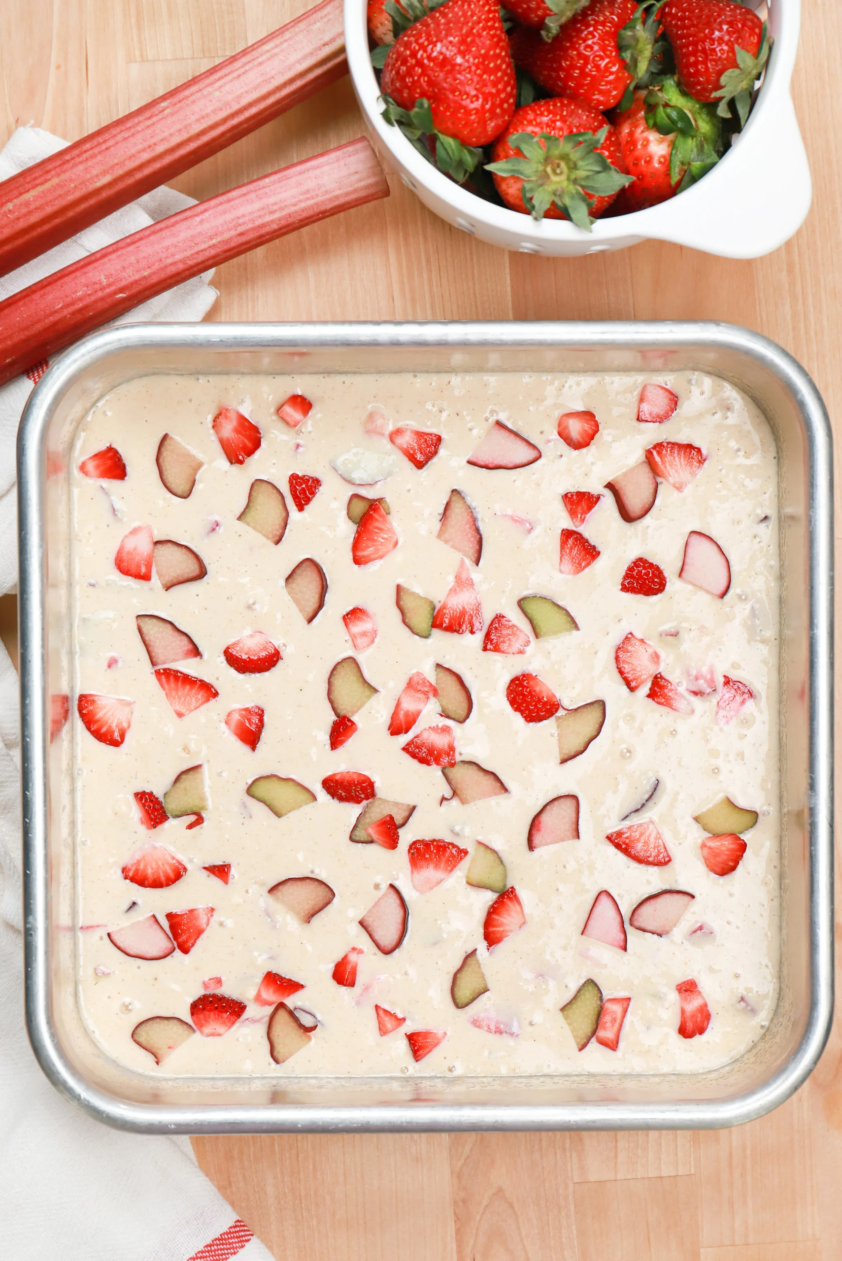 Overhead view of the strawberry rhubarb crumb cake batter in the baking dish before baking.