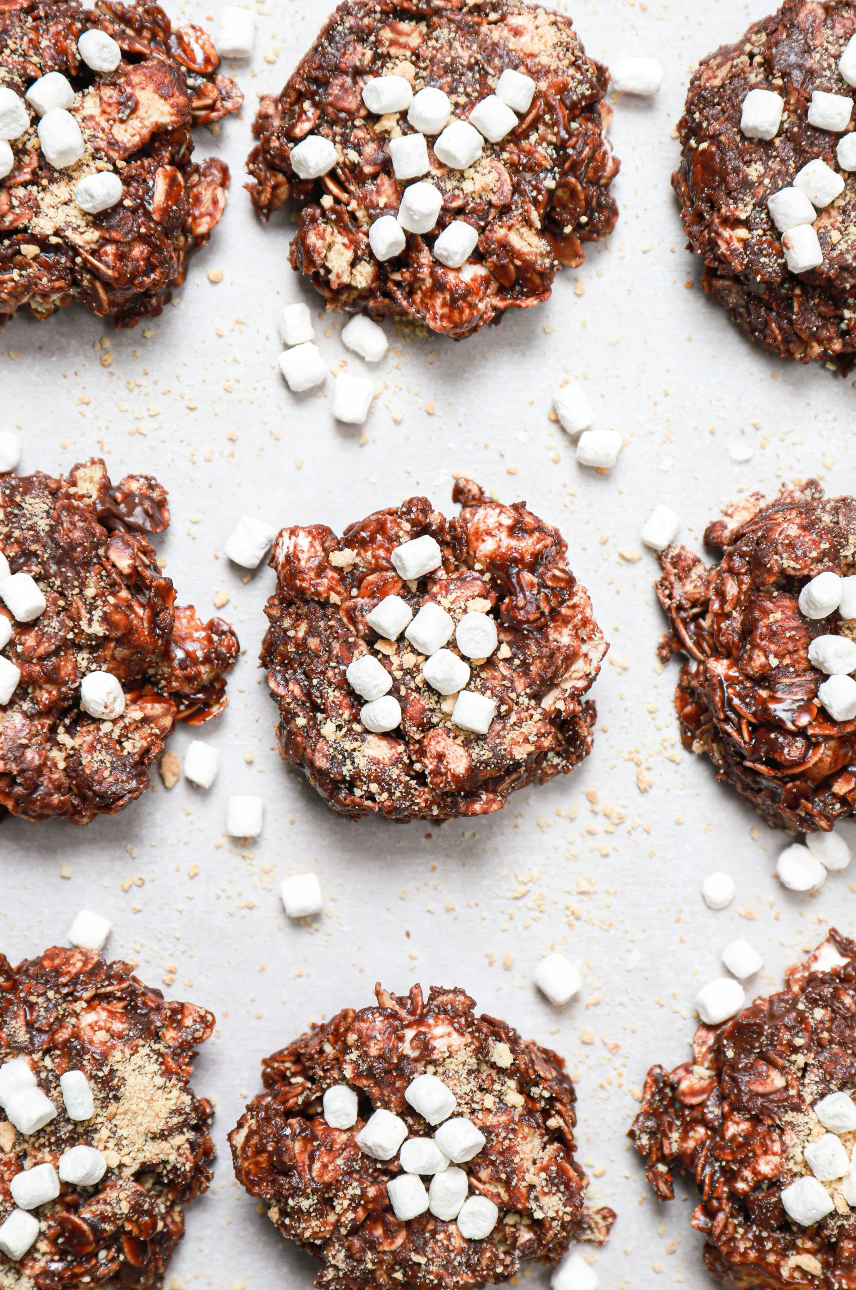 Close up overhead view of a batch of dark chocolate no bake cookies on a parchment paper lined baking sheet.