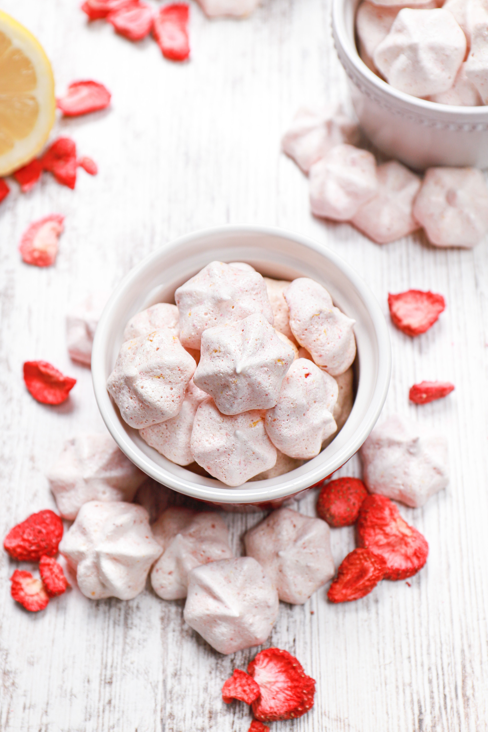 Overhead view of a small bowl full of mini strawberry lemon meringue cookies.