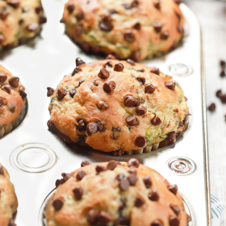 Up close side view of the top of a chocolate chip zucchini muffin in a muffin tin.