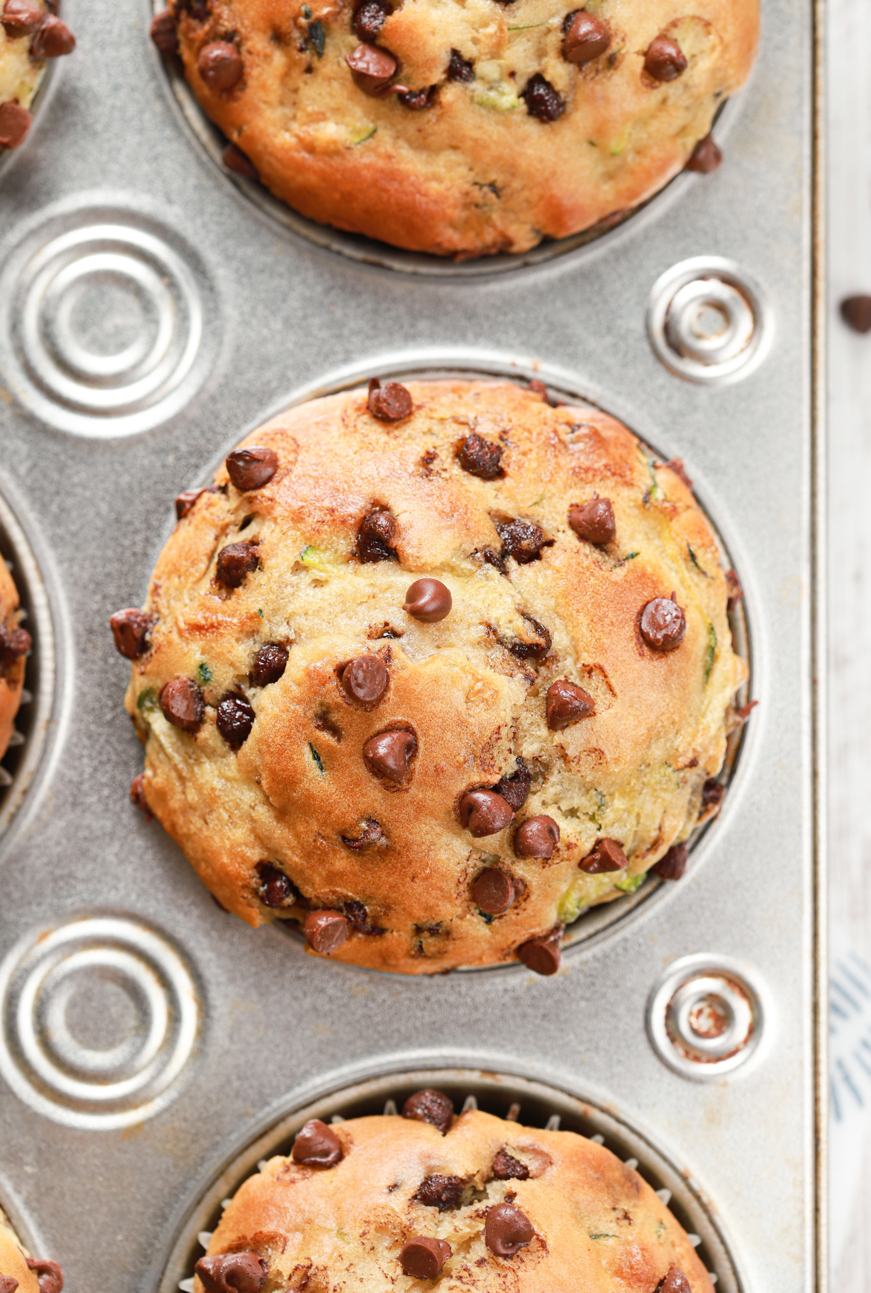 Up close overhead view of a bakery style chocolate chip zucchini muffin in a muffin tin.