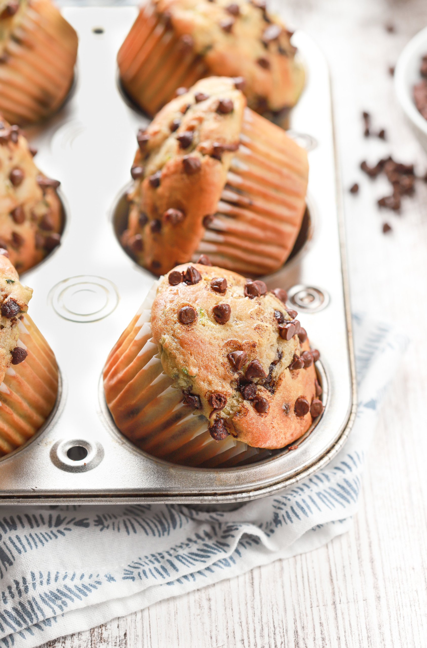 A batch of bakery style chocolate chip zucchini muffins in a muffin tin.