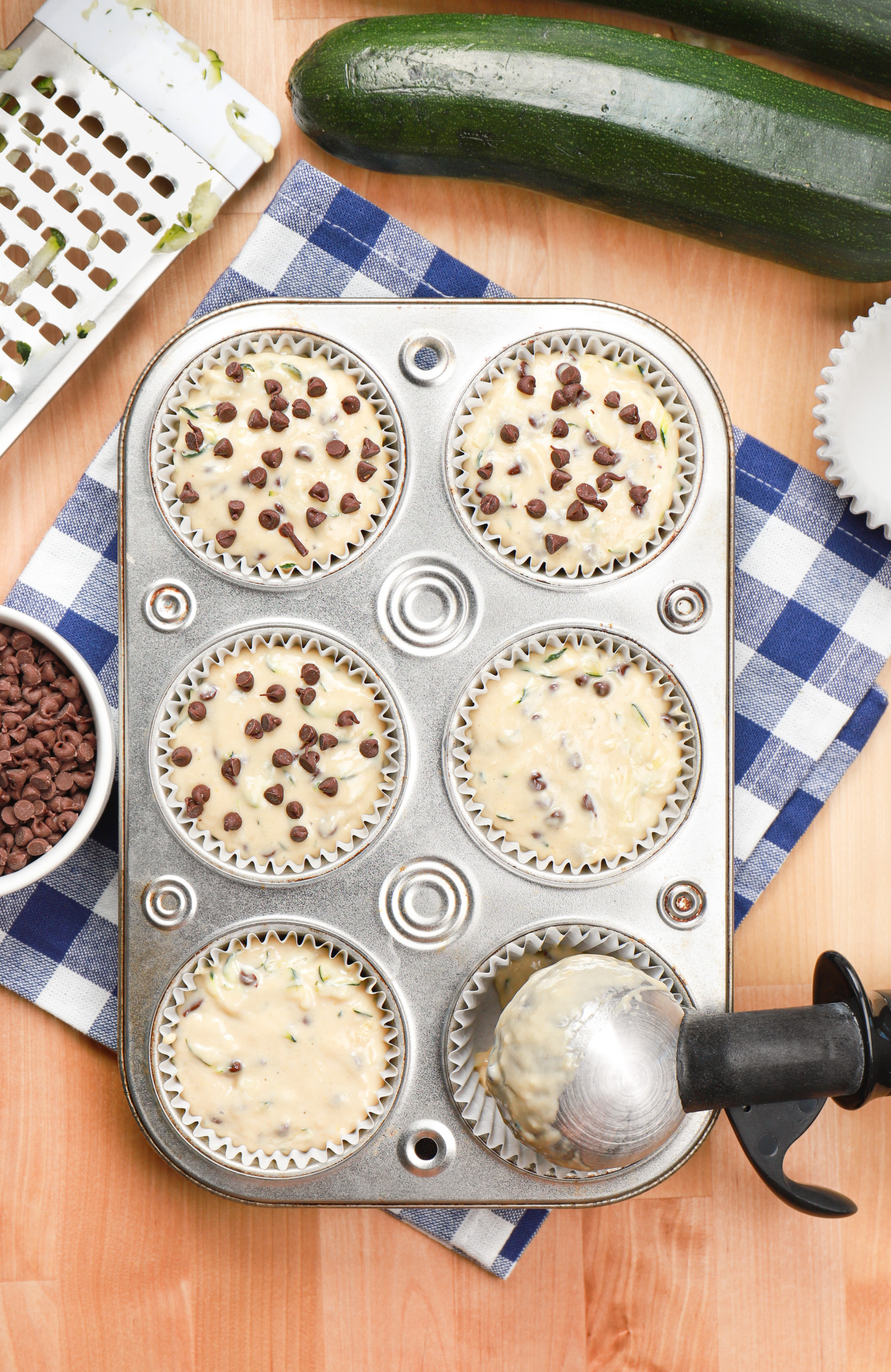 Overhead view of chocolate chip zucchini muffin batter in a muffin tin.