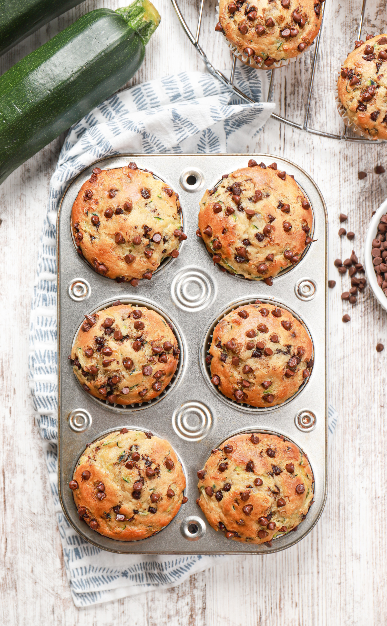 Overhead view of a batch of chocolate chip zucchini muffins in a muffin tin.