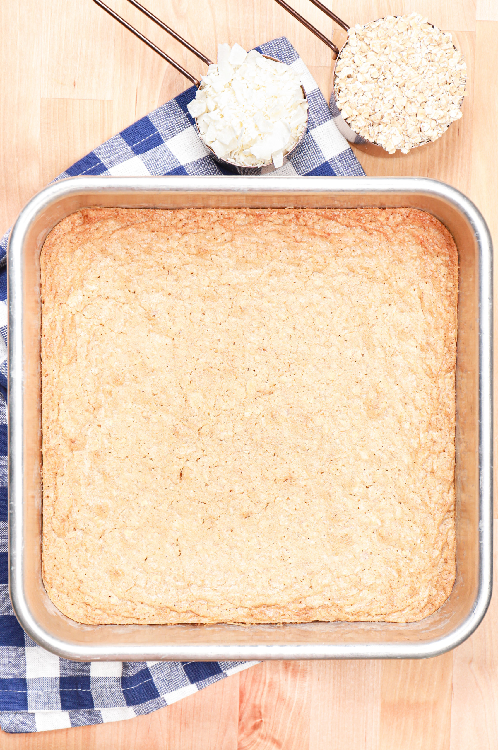 Overhead view of a batch of coconut oat bars in a baking dish before frosting.