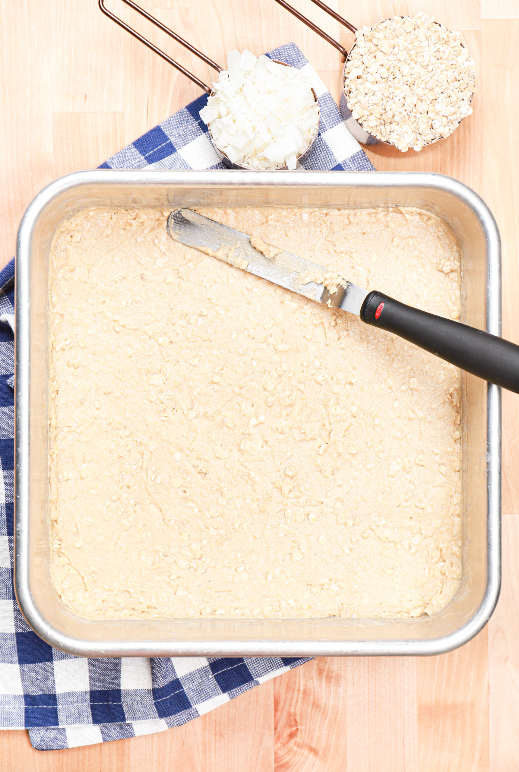 Overhead view of a coconut oat bar batter in a baking dish before baking.