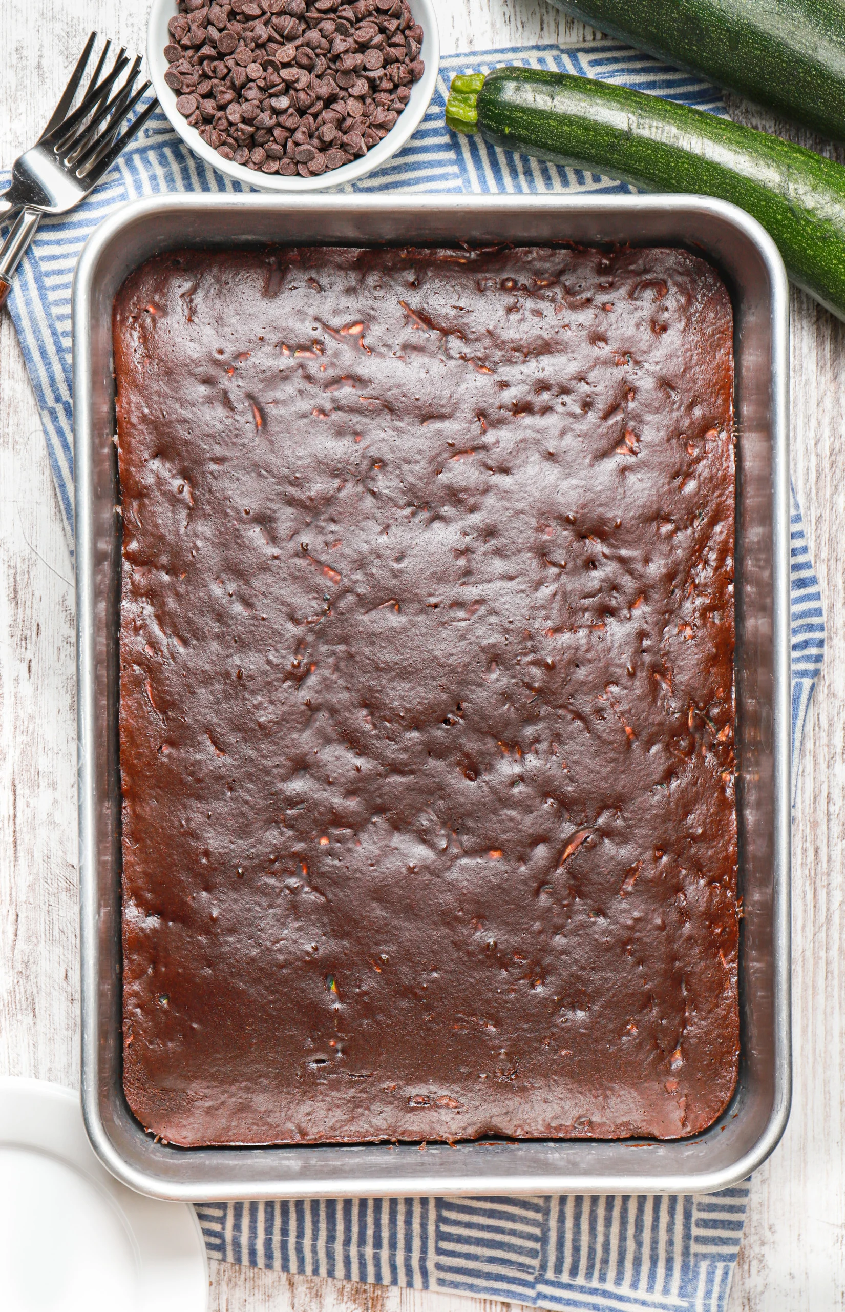 Overhead view of a batch of chocolate zucchini bars in an aluminum baking dish before chocolate frosting is added.
