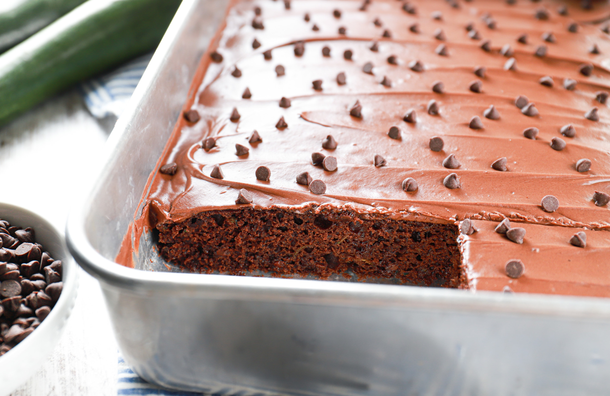 Side view of a row of frosted chocolate zucchini bars in their baking dish.