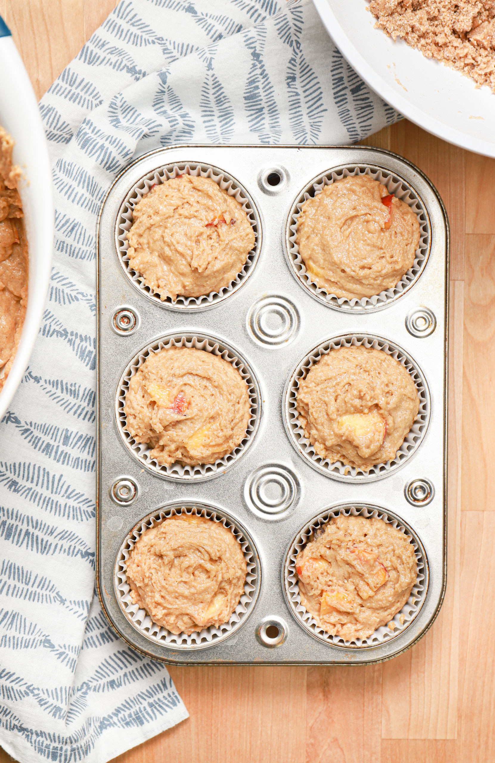 Overhead view of peach muffin batter in a muffin tin.