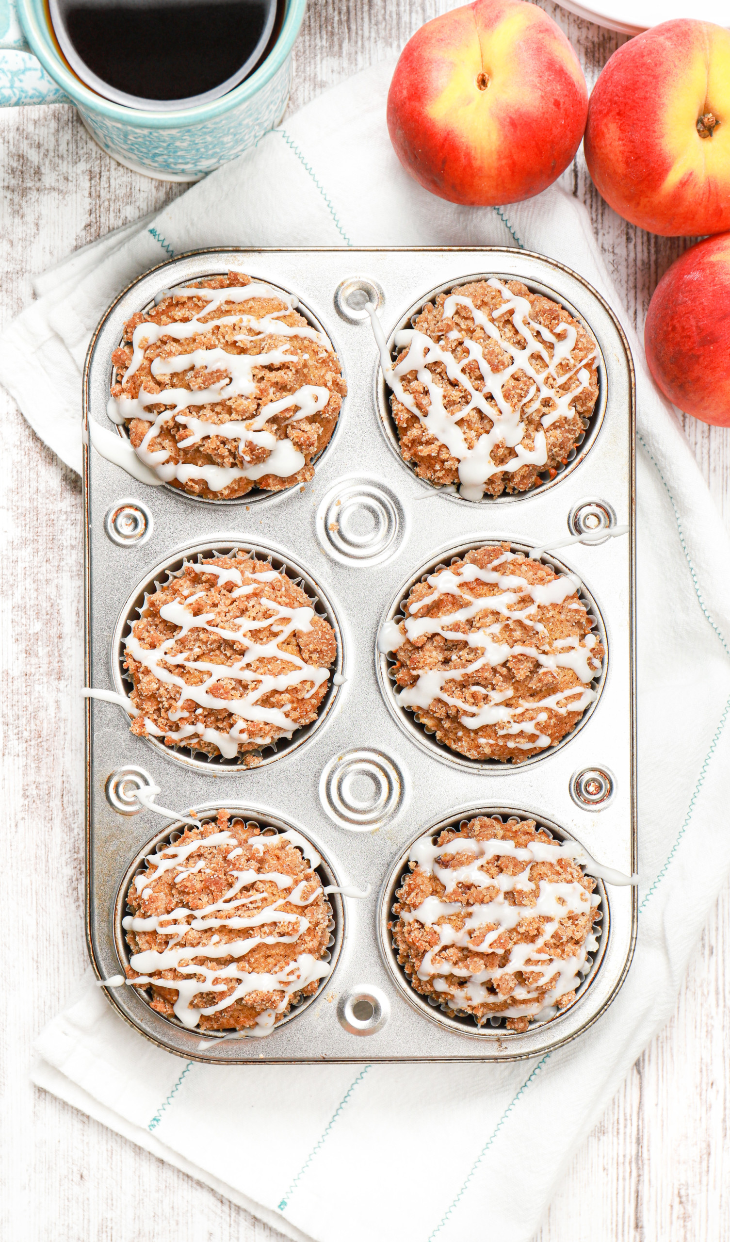 Overhead view of a batch of peach coffee cake muffins in a muffin tin.