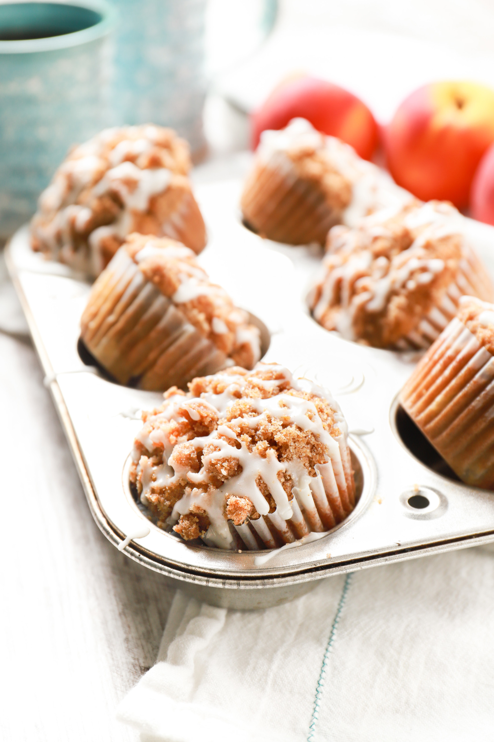 Side view of a batch of peach streusel muffins in an aluminum muffin tin.